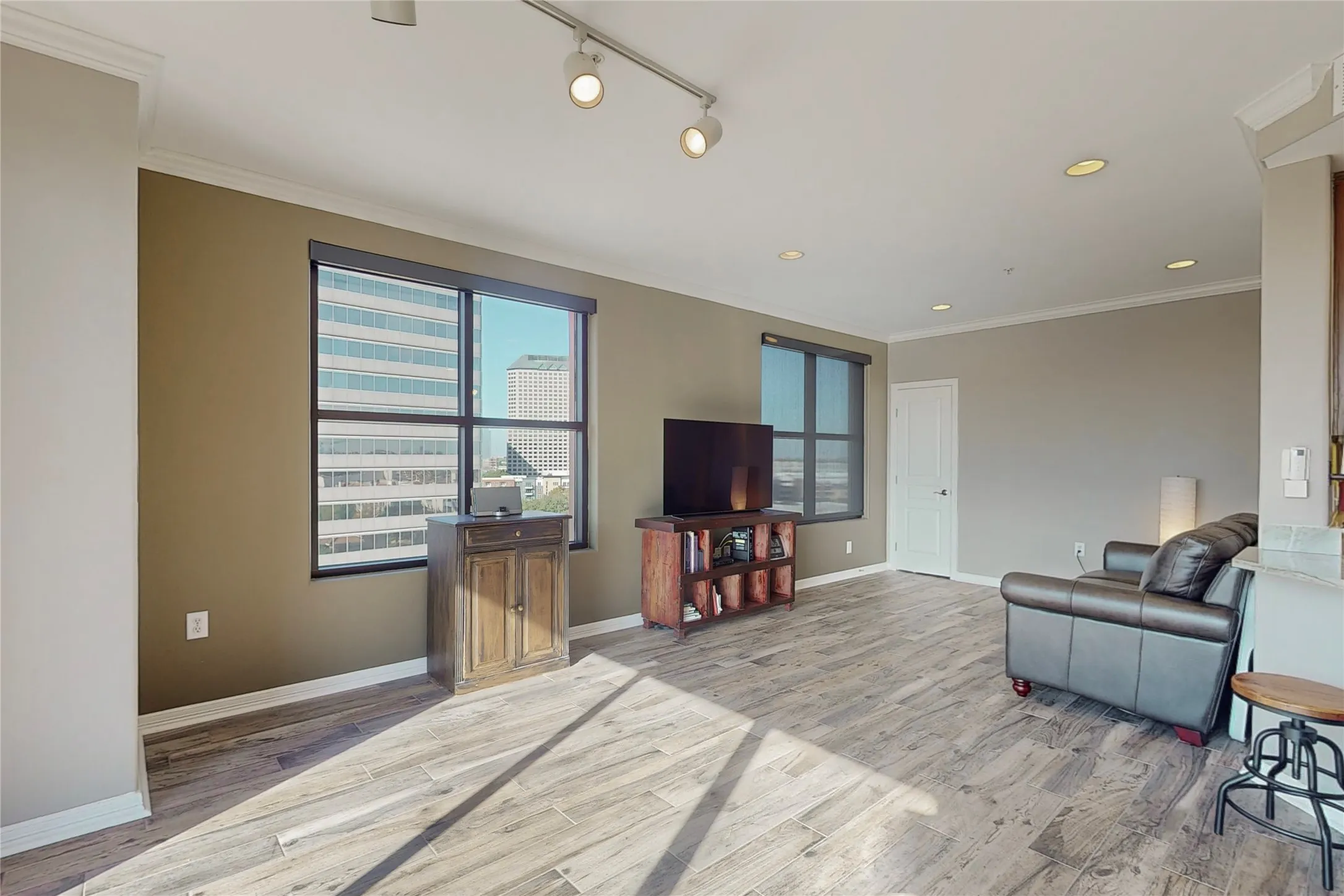 Living room featuring ornamental molding, rail lighting, and light wood-type flooring