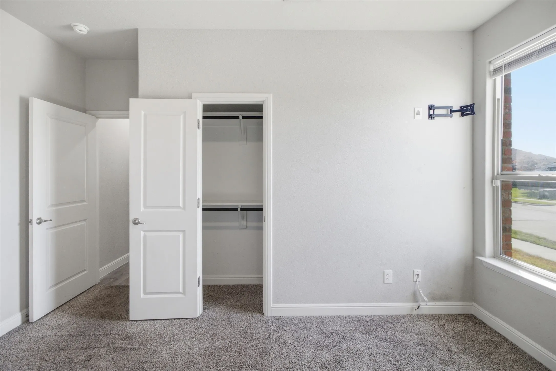 Neutral wall finishes, window with natural light, integrated closet shelving and hanging rods, plush carpeting