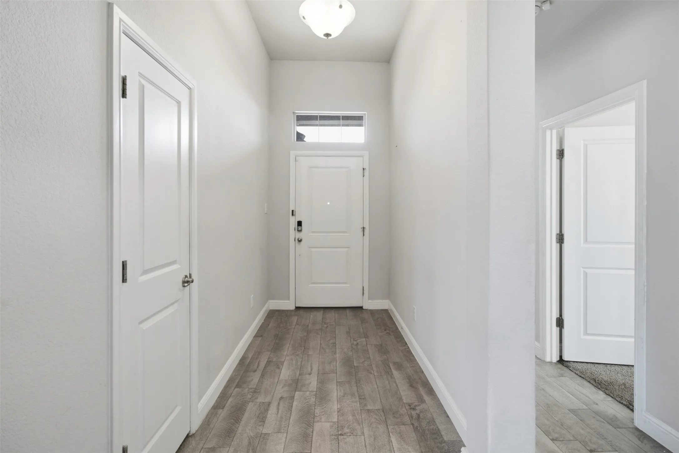 Entryway featuring wood-finish flooring and a transom window above the main door