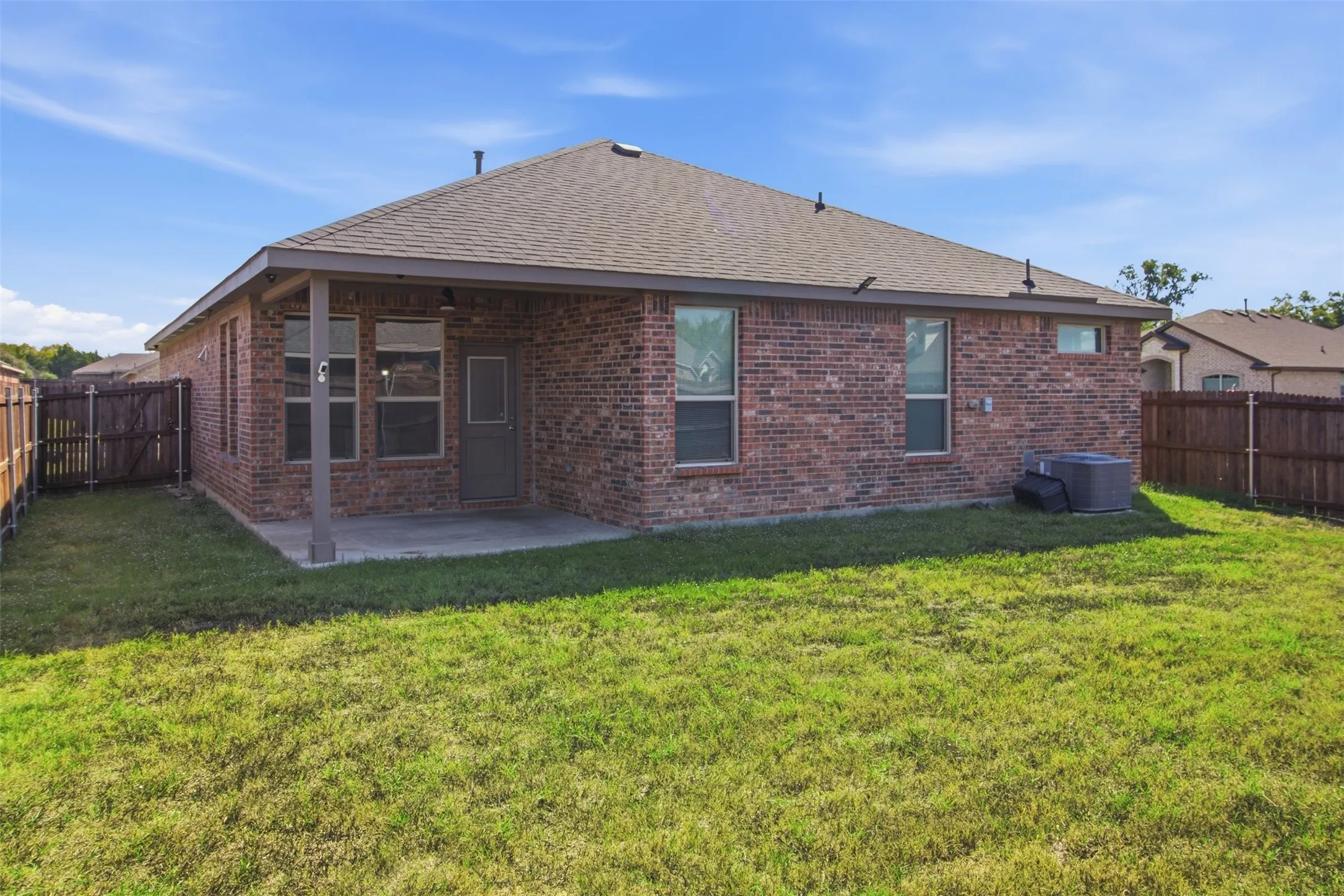 Brick exterior with covered patio, fenced yard, and multiple windows