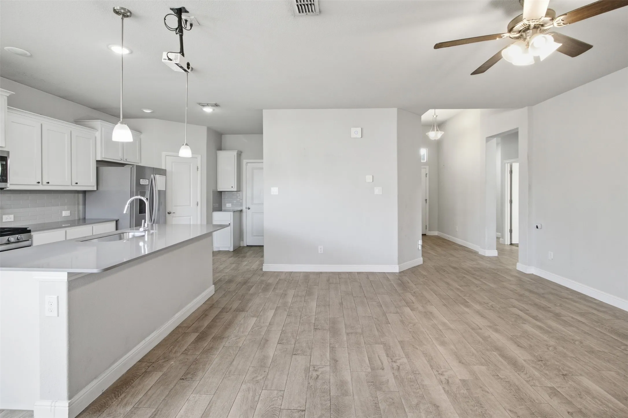 Spacious room featuring wood-finish flooring, recessed lighting, and a ceiling fan