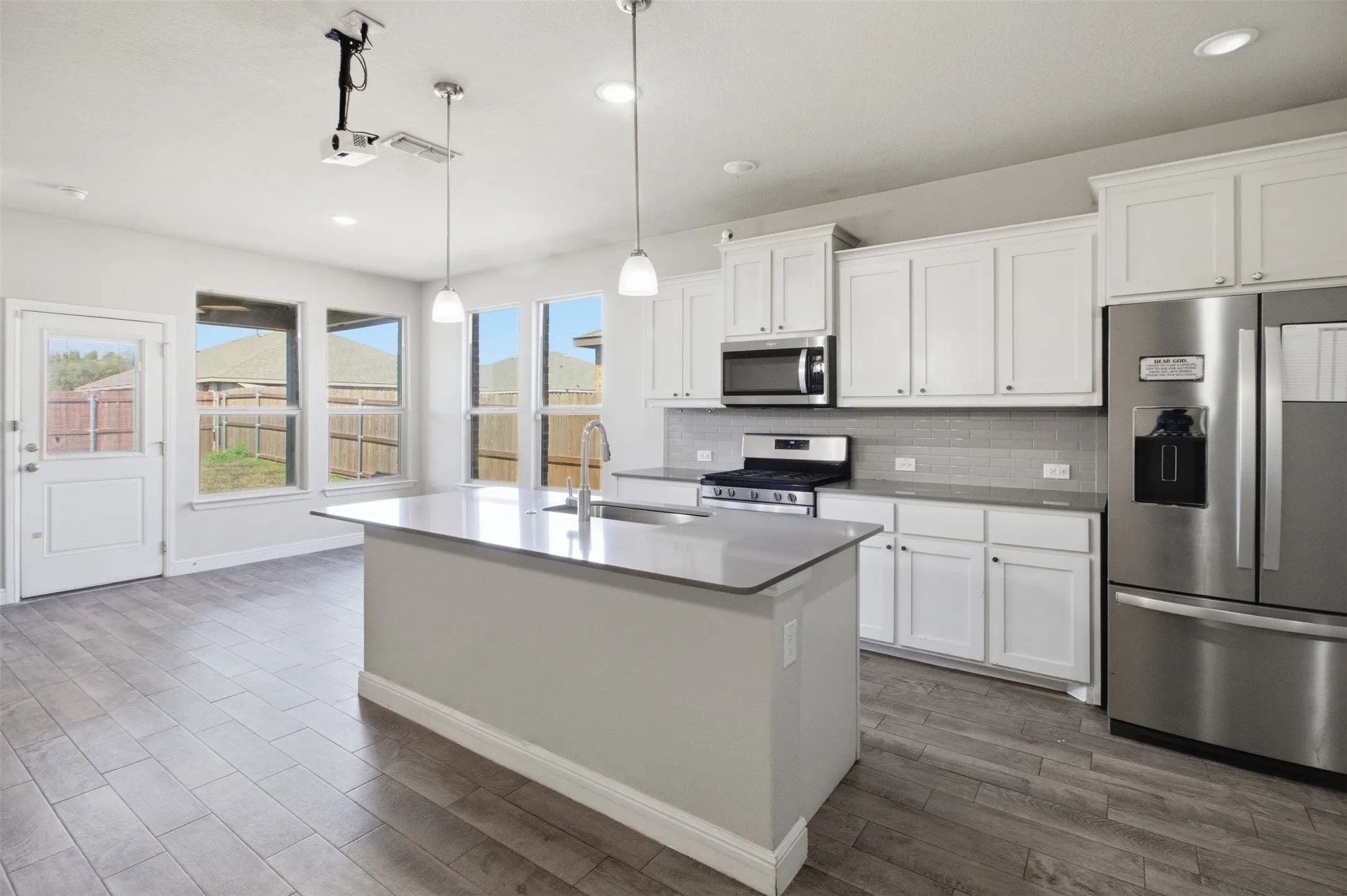 Kitchen featuring a center island, stainless steel appliances, white cabinetry, and wood-finish flooring