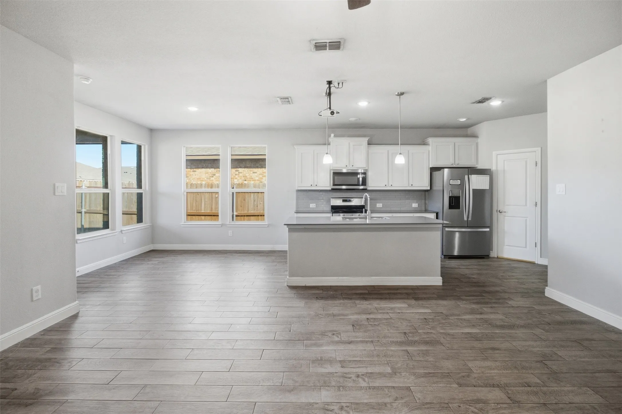 Spacious open-concept layout with wood-finish flooring, recessed lighting, and multiple windows
