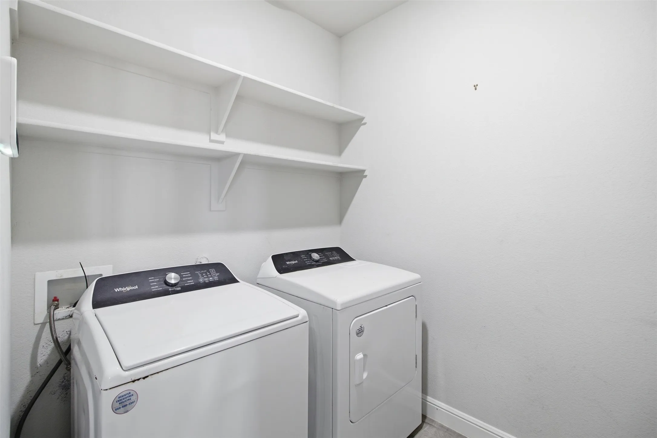 Laundry area featuring two white built-in shelves