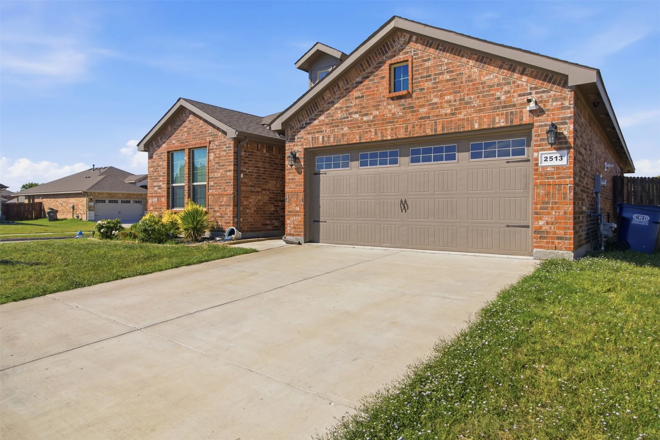 Brick exterior with a gabled roofline, concrete driveway, and a two-car garage with transom windows