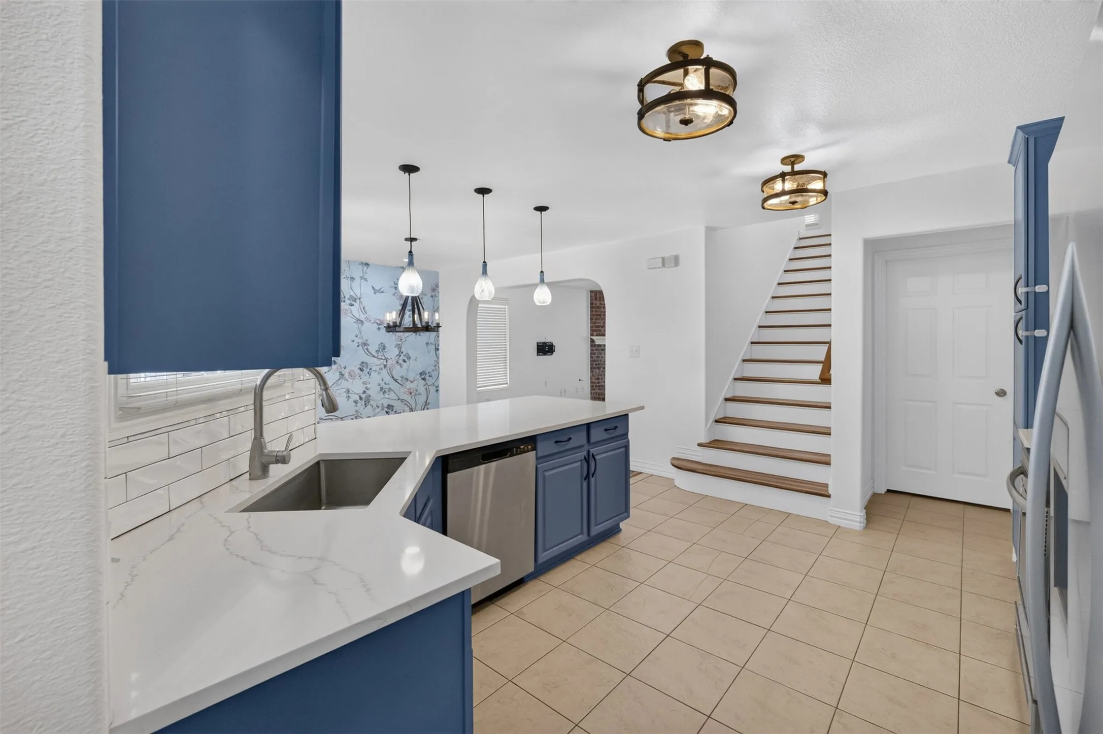 Kitchen featuring blue cabinetry, a stainless steel sink, a white countertop, and subway tile backsplash