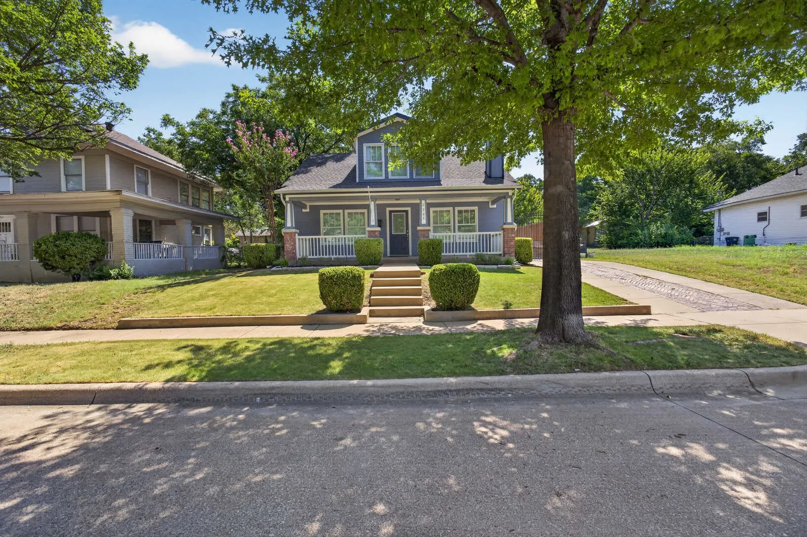 Two-story residence with a dormer window, covered front porch, and a stone-lined driveway