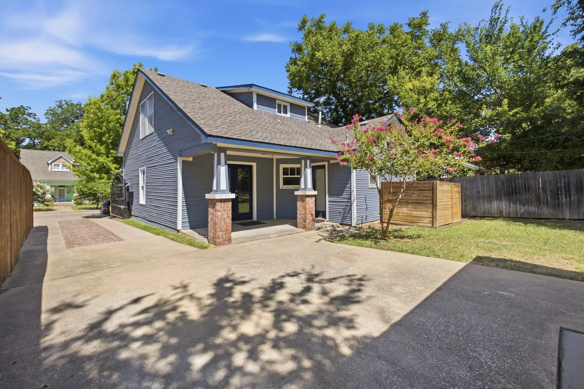 Siding exterior with dormer windows, covered entry, and brick column accents