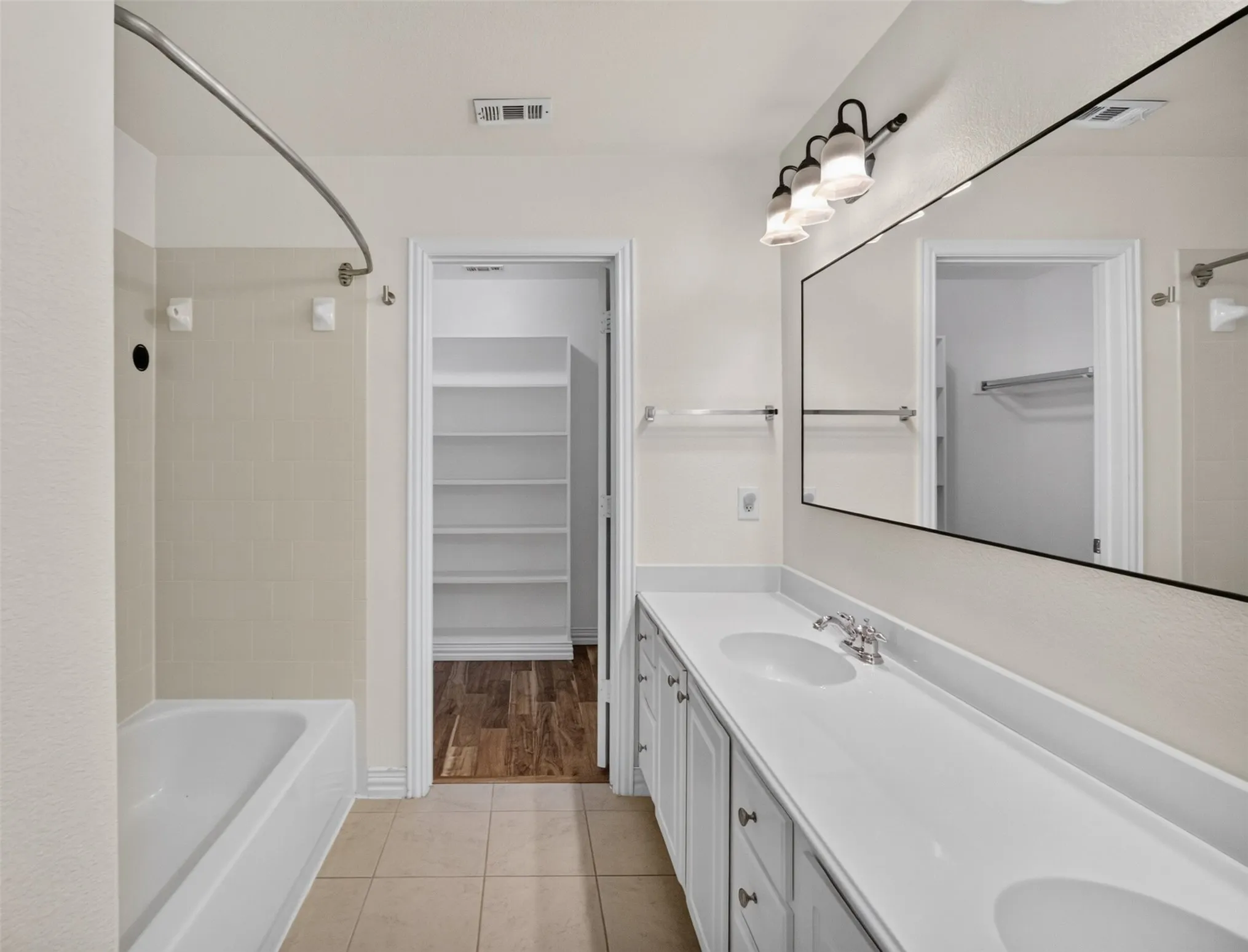 Dual vanity with undermount sinks, white countertop, and tiled flooring
