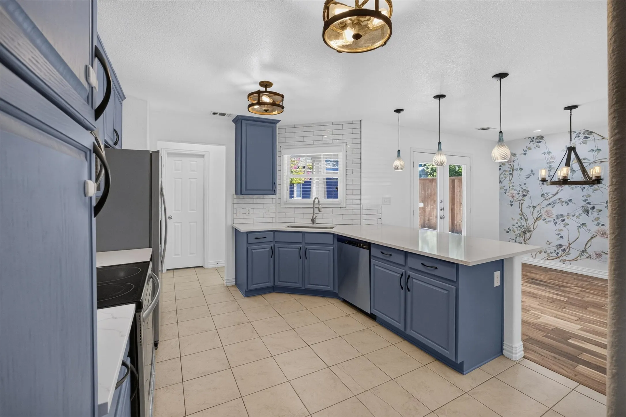 Kitchen featuring blue shaker-style cabinetry, stainless steel appliances, a white subway tile backsplash, and light-colored countertops