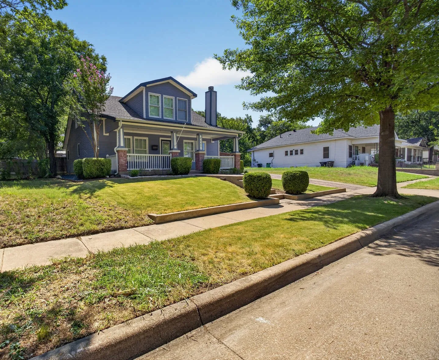 Traditional style architecture with a covered front porch, brick accent columns, and a prominent chimney