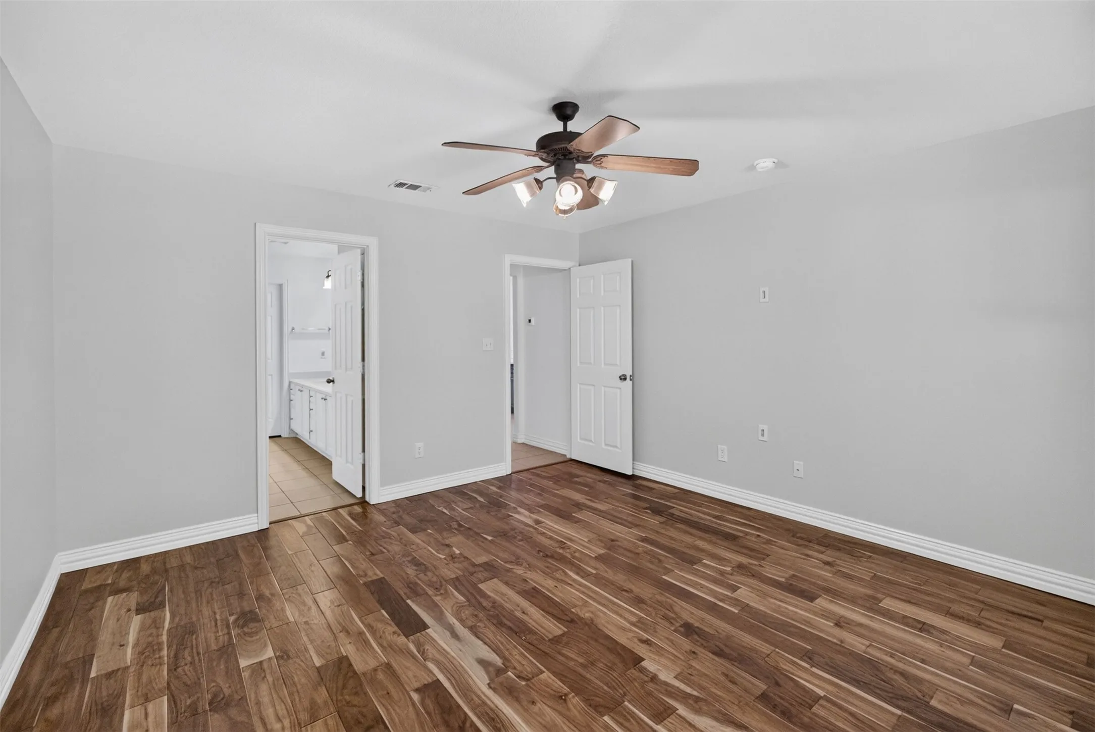 Wood-finish flooring with light gray walls, a ceiling fan with integrated lighting, and a recessed light fixture
