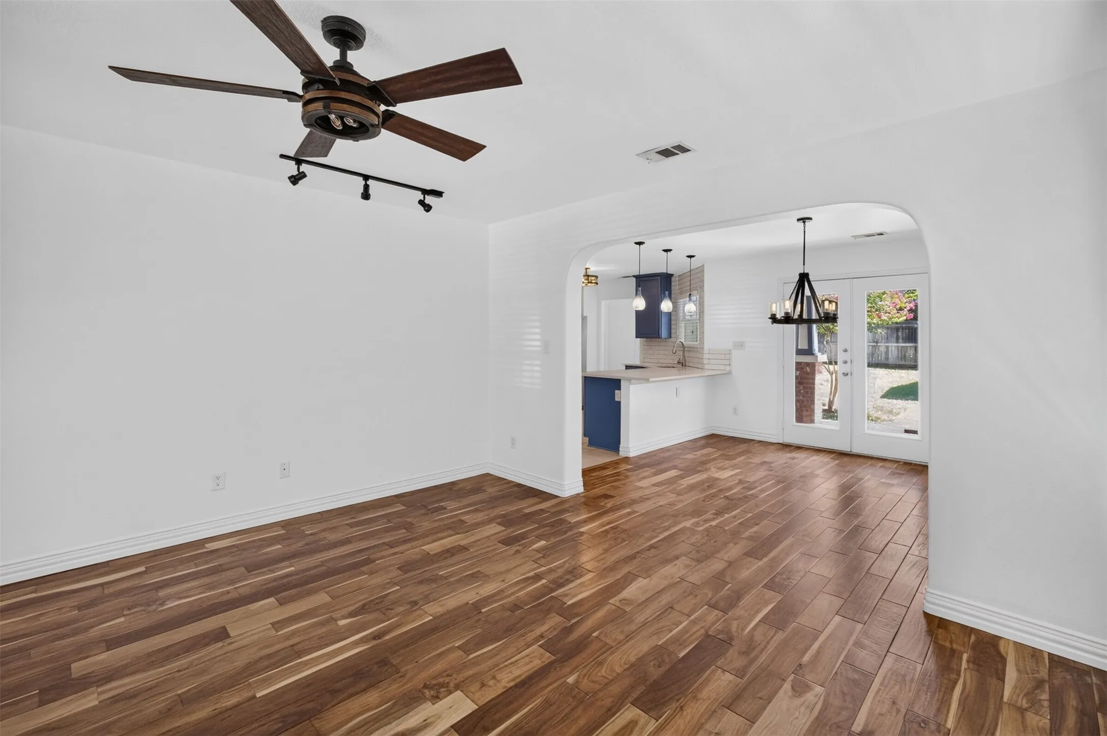 Wood-finish flooring throughout, with a decorative ceiling fan and track lighting