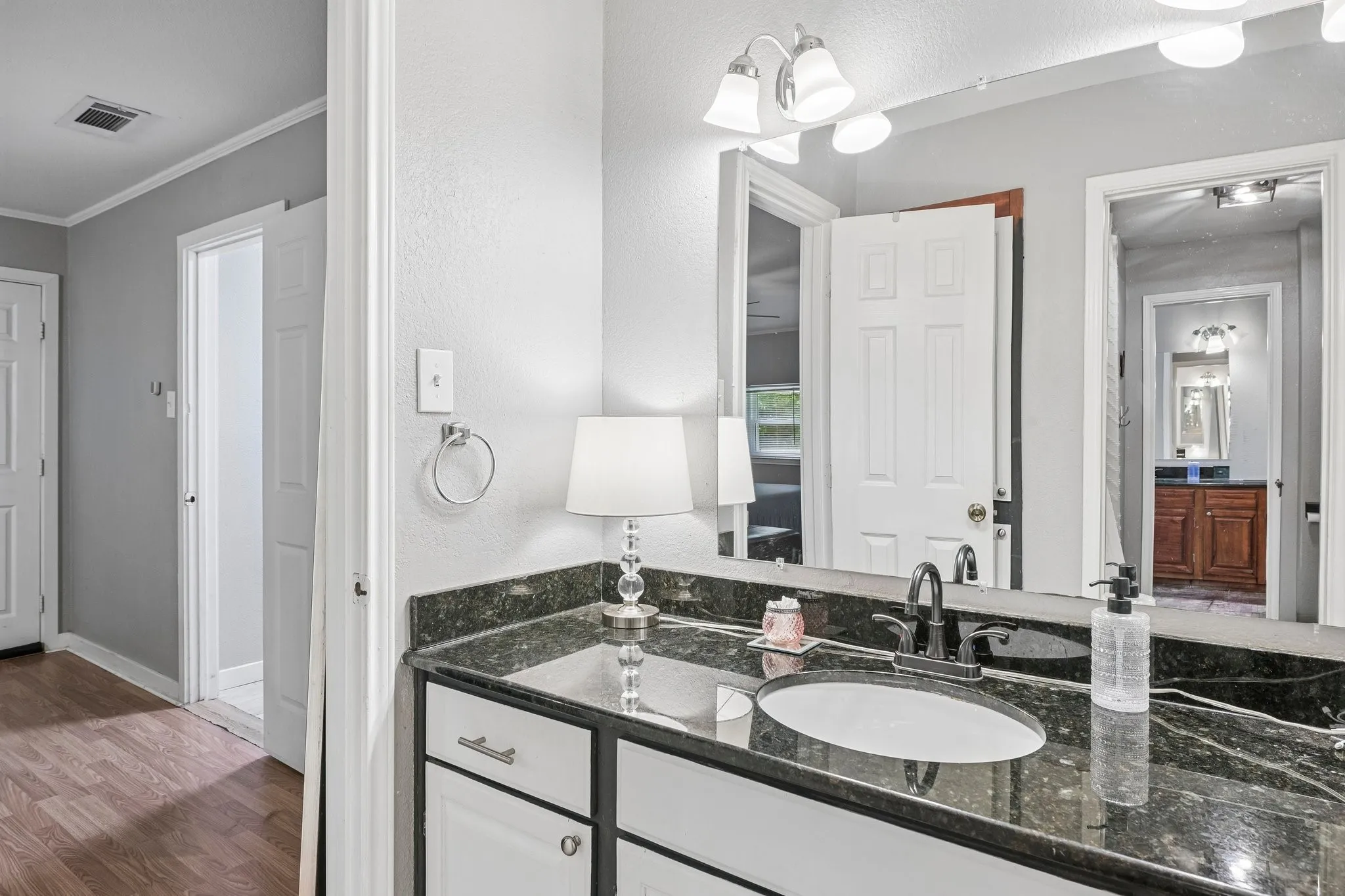 Vanity with white cabinetry, dark countertop, and an oval undermount sink