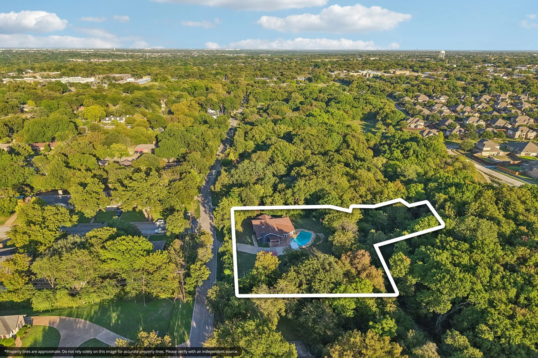 Expansive lot featuring mature trees, a swimming pool, and a residential structure with an attached garage