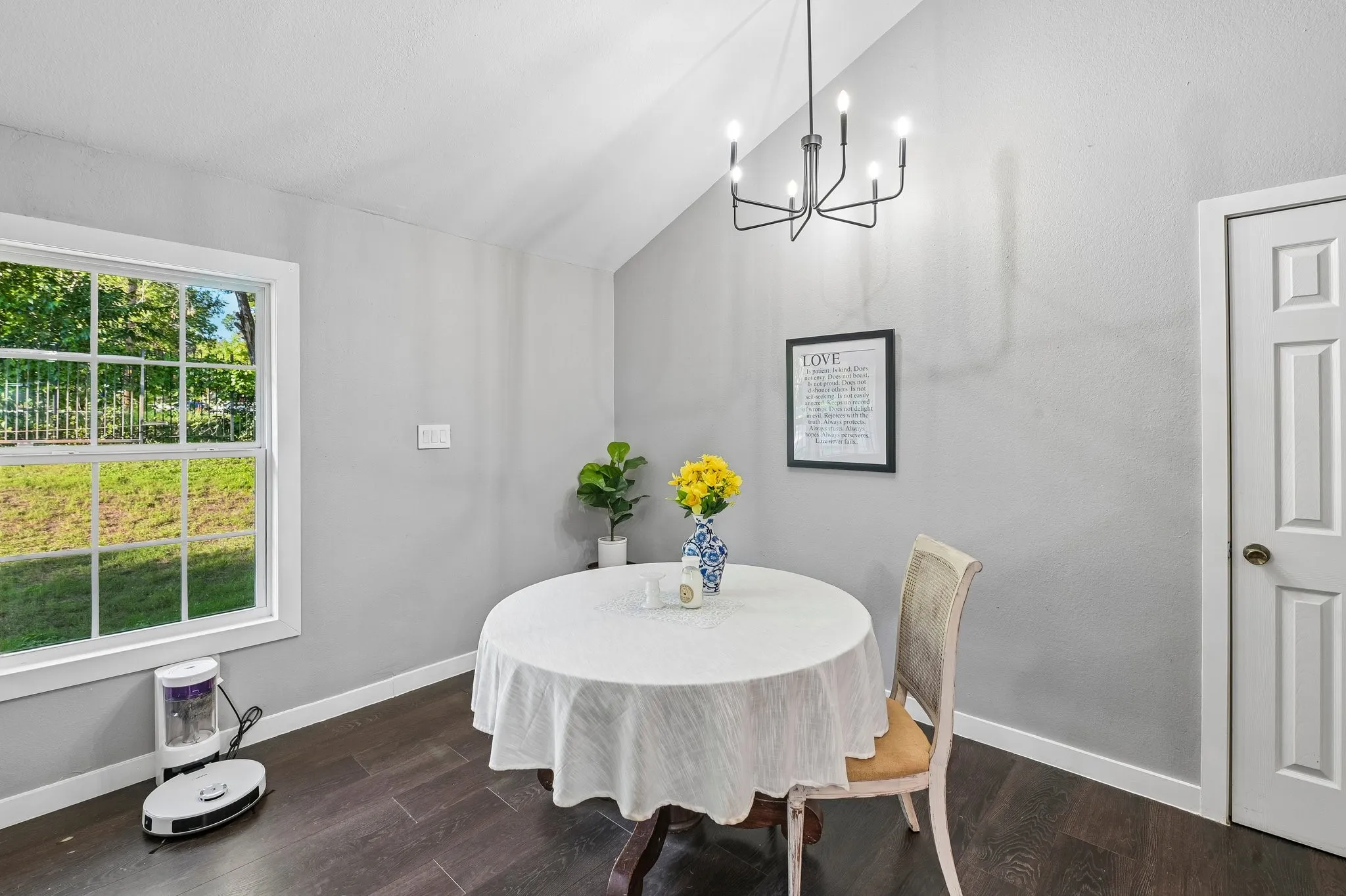 Vaulted ceiling with contemporary chandelier, wood-finish flooring, and white trim