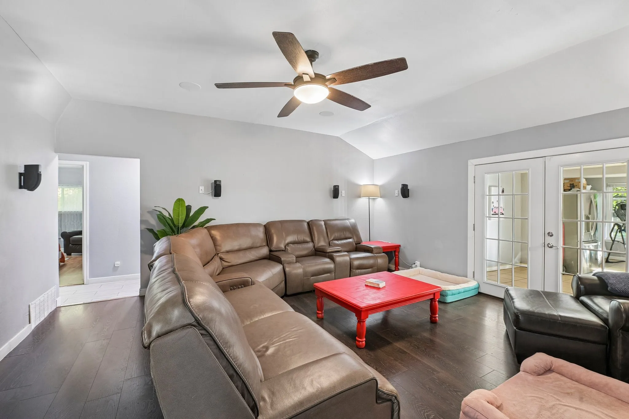 Vaulted ceiling with a ceiling fan, dark wood-finish flooring, light gray wall paint, and double French doors with glass panes