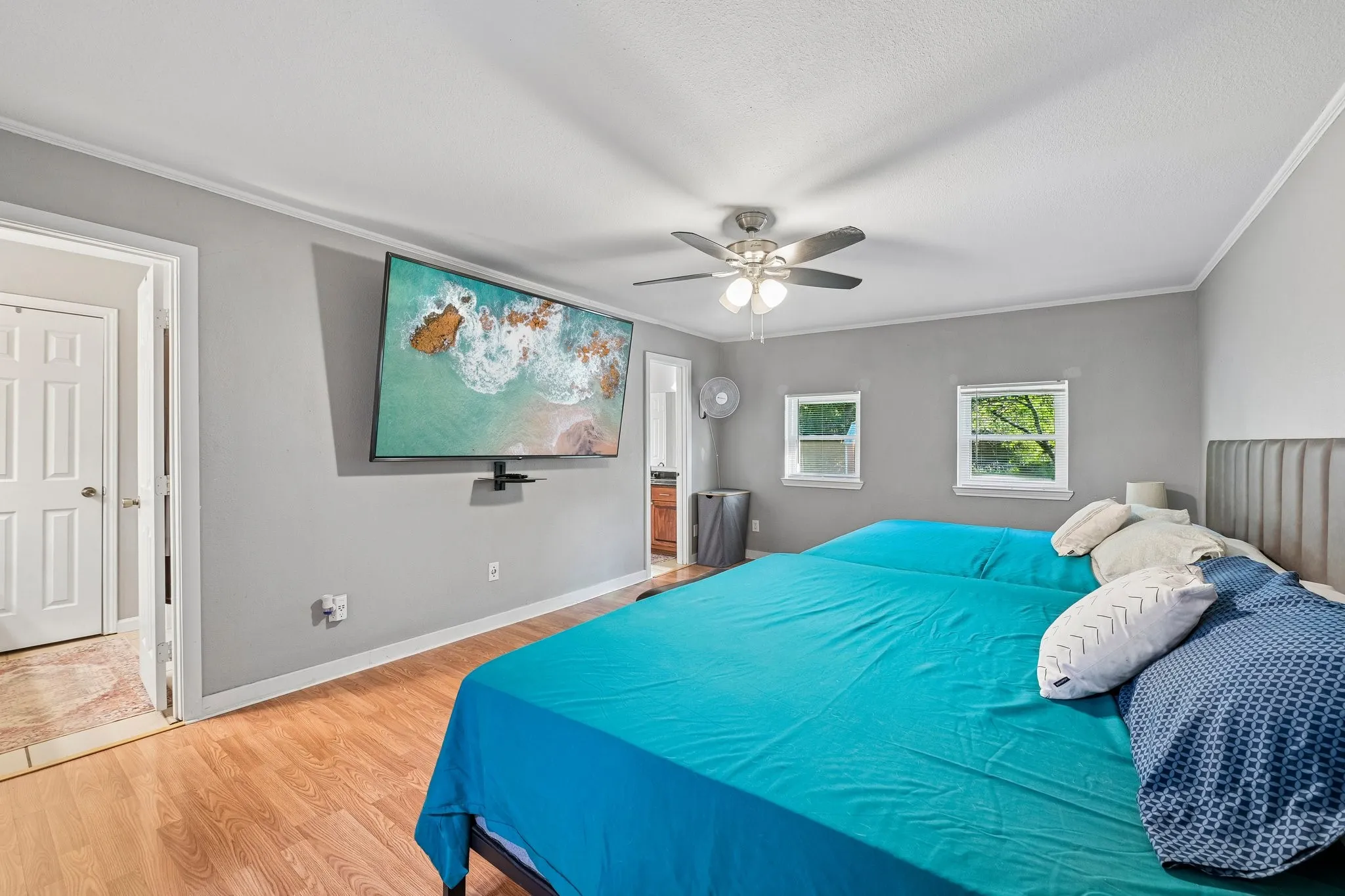 Wood-finish flooring, two windows, and a ceiling fan with integrated lighting