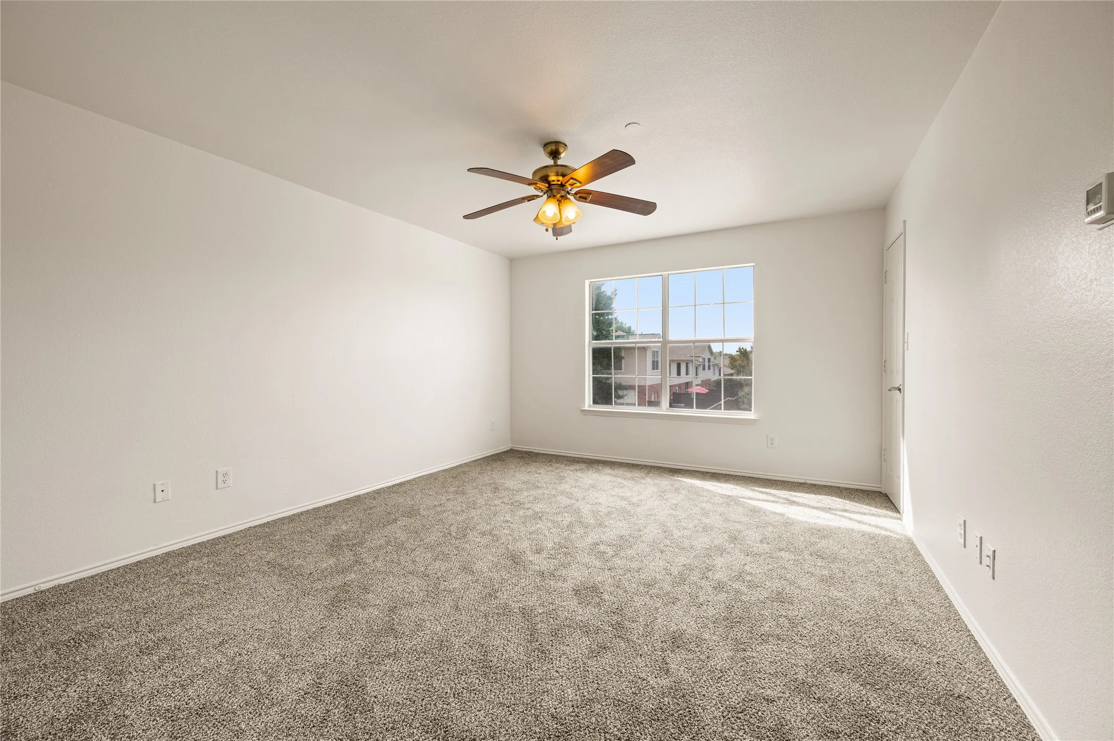 Plush carpet flooring, a multi-pane window, and a ceiling fan with integrated lighting