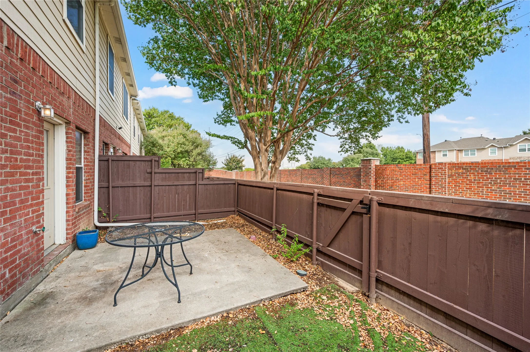 Private outdoor patio with concrete paving, mature tree, and wood privacy fencing