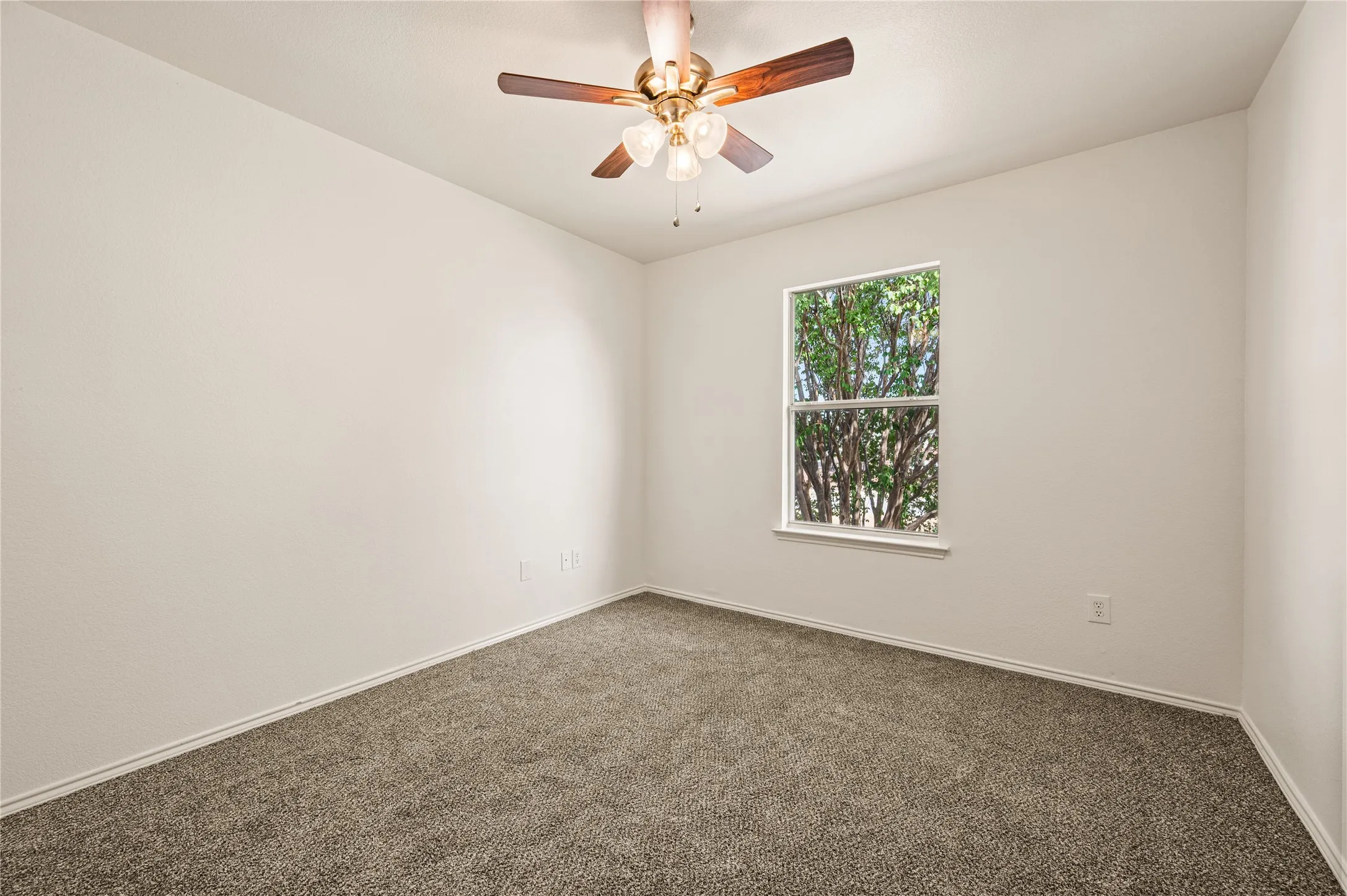 Neutral tone walls, ceiling fan with light fixture, window providing natural illumination, and carpeting