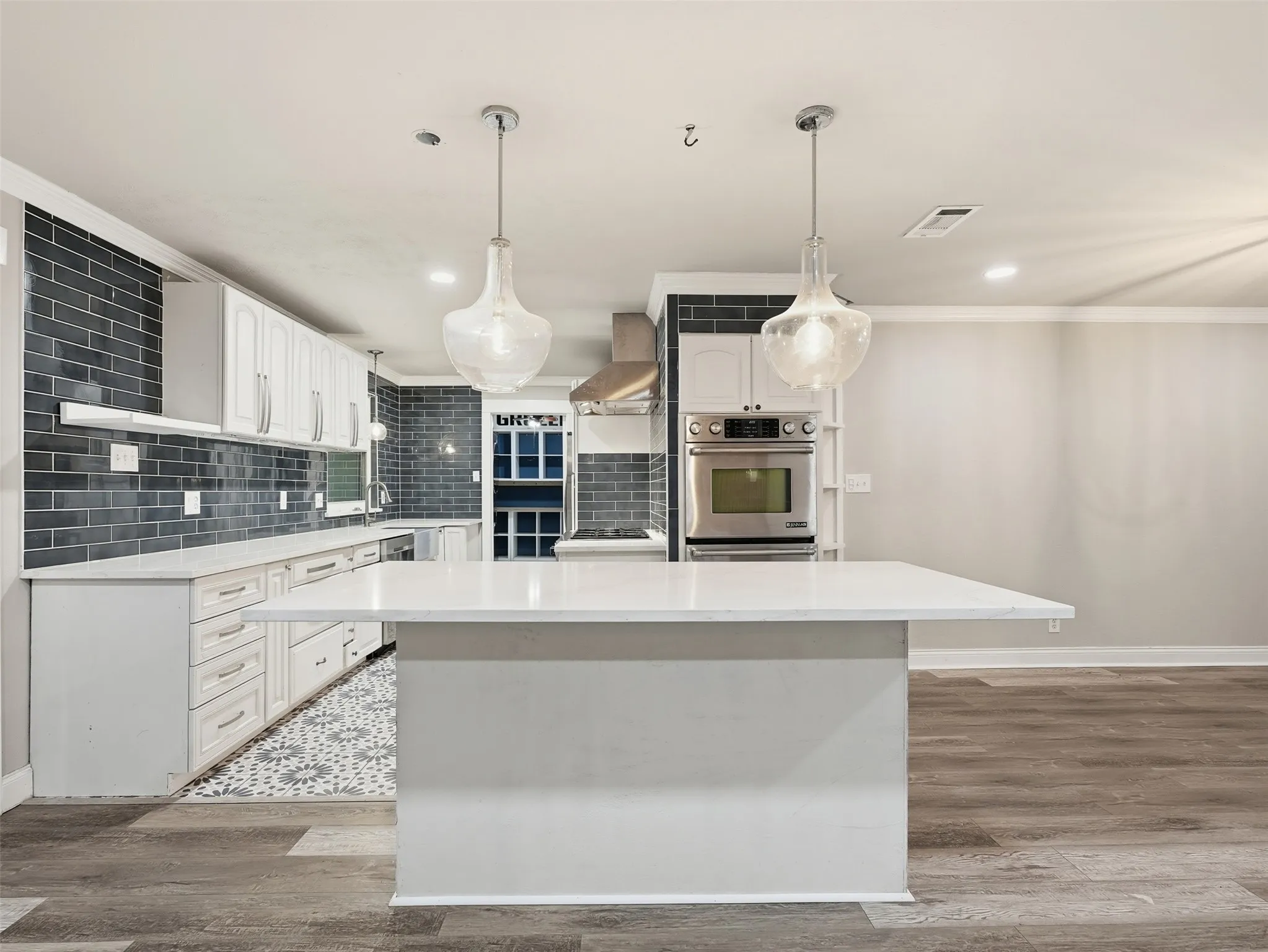 Contemporary kitchen featuring white cabinetry, a large center island with a light-toned countertop, and stainless steel built-in appliances