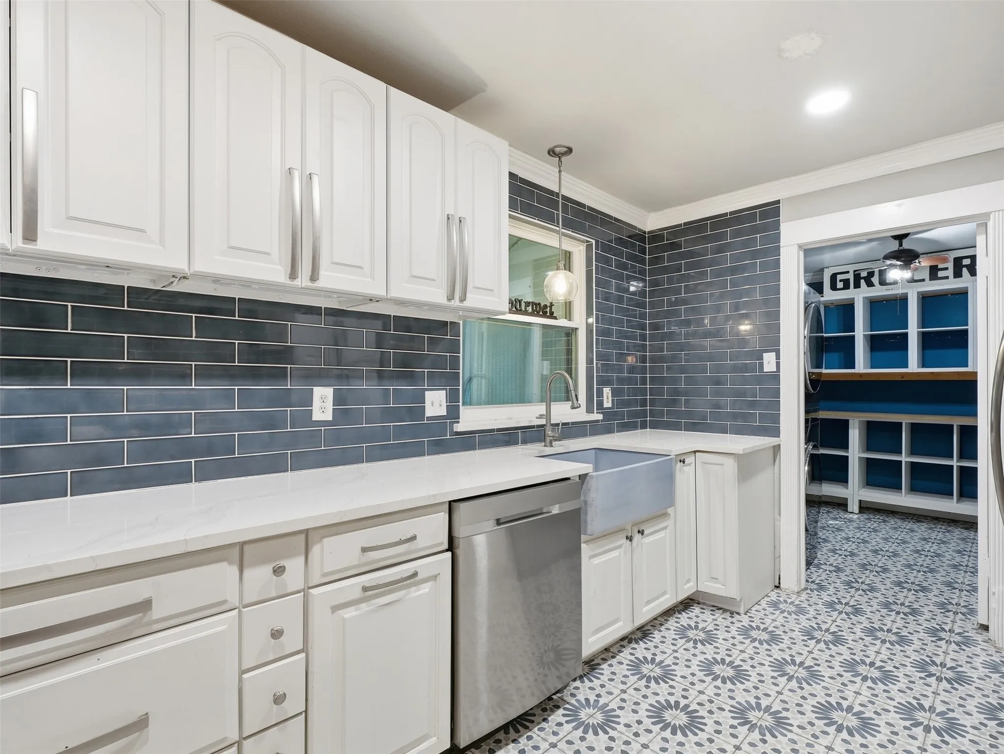 White cabinetry, blue subway tile backsplash, white countertops, farmhouse sink, and patterned floor tiling