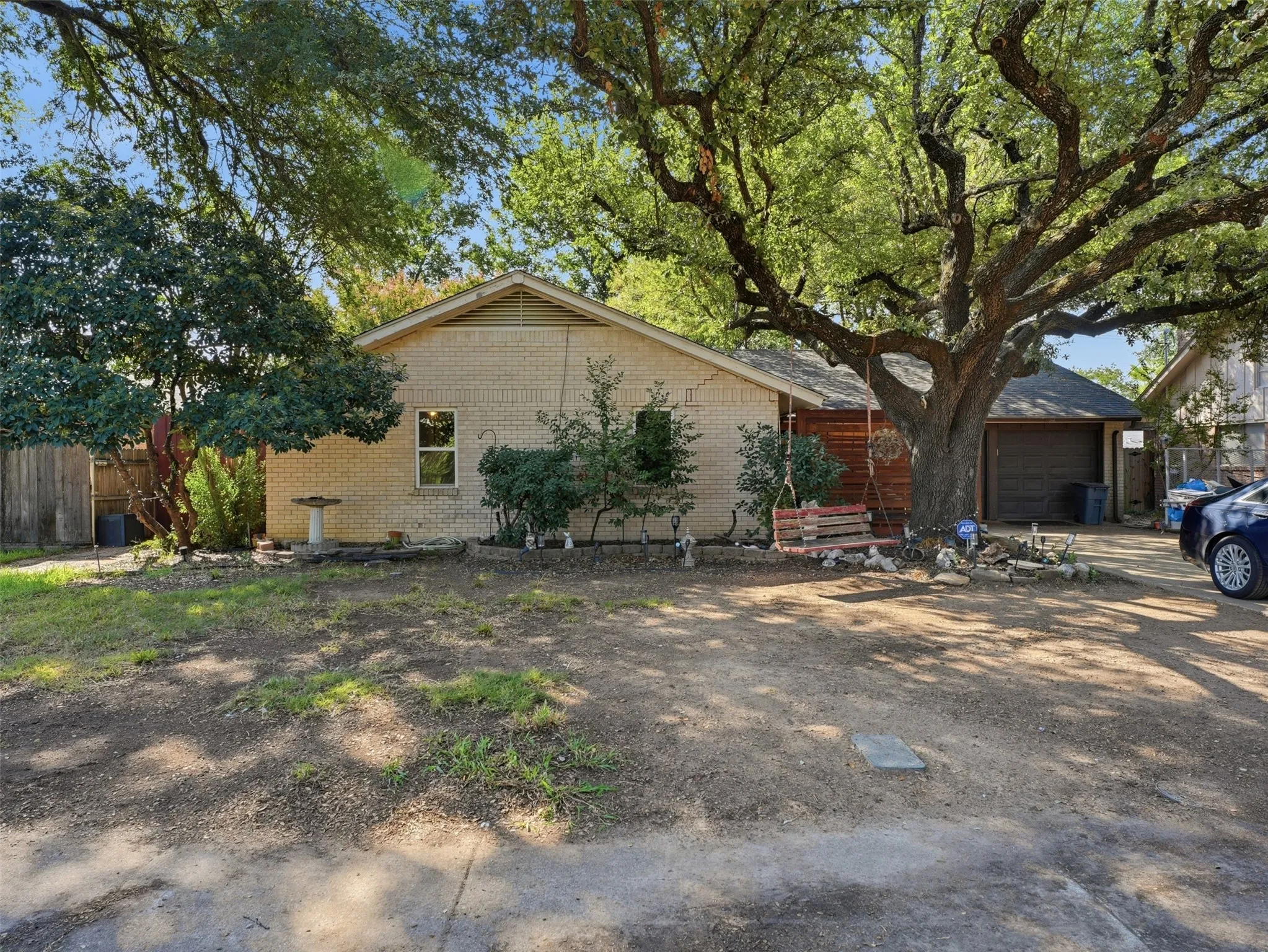 Brick exterior with a prominent mature shade tree and attached garage
