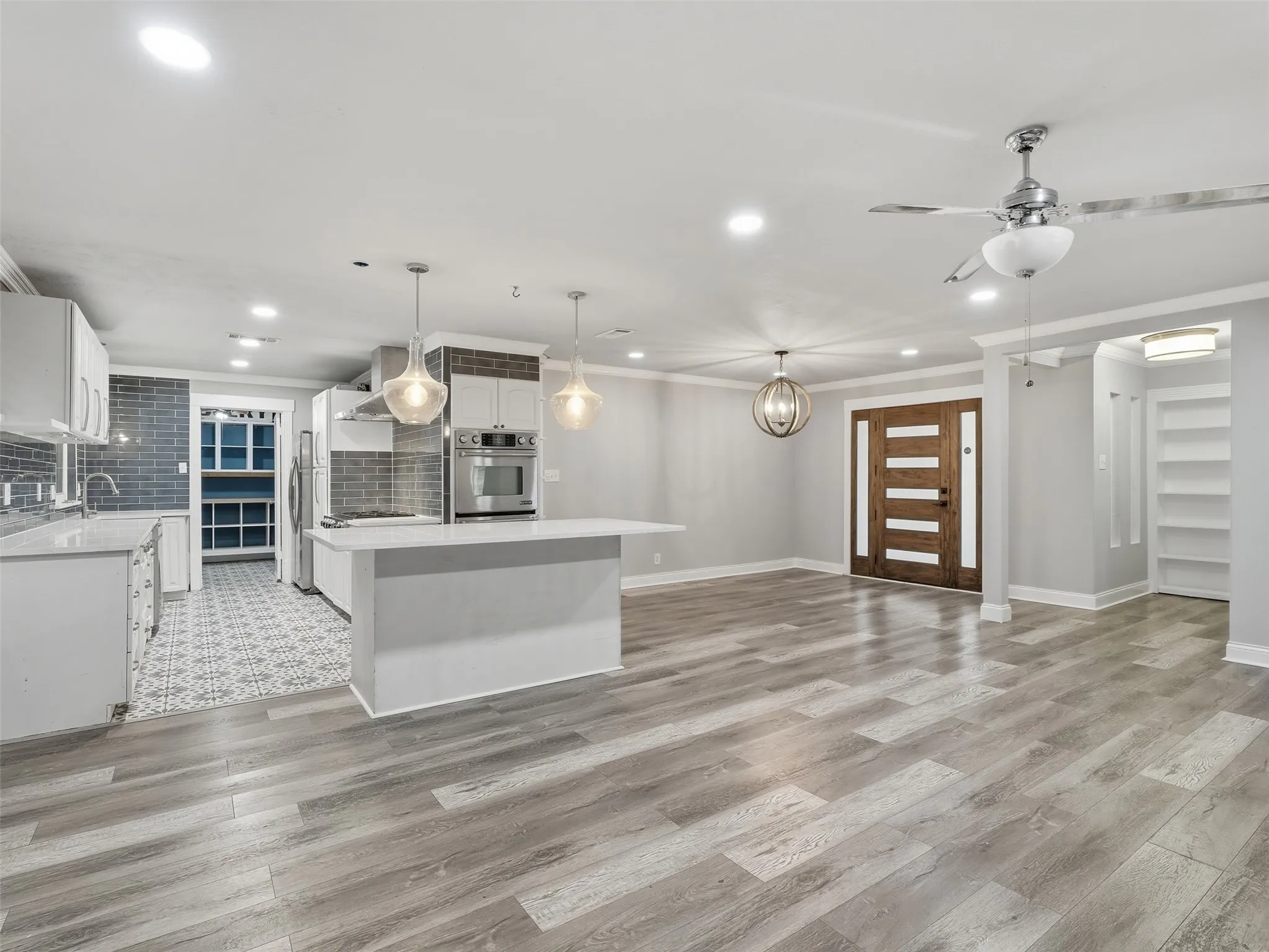Expansive open-concept living space with wood-finish flooring, recessed lighting, and a modern ceiling fan