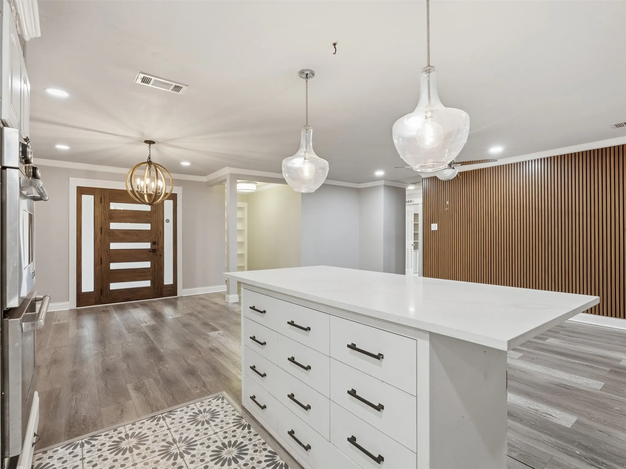 Kitchen island with a white countertop and drawer storage, wood-finish flooring, and two clear glass pendant lights