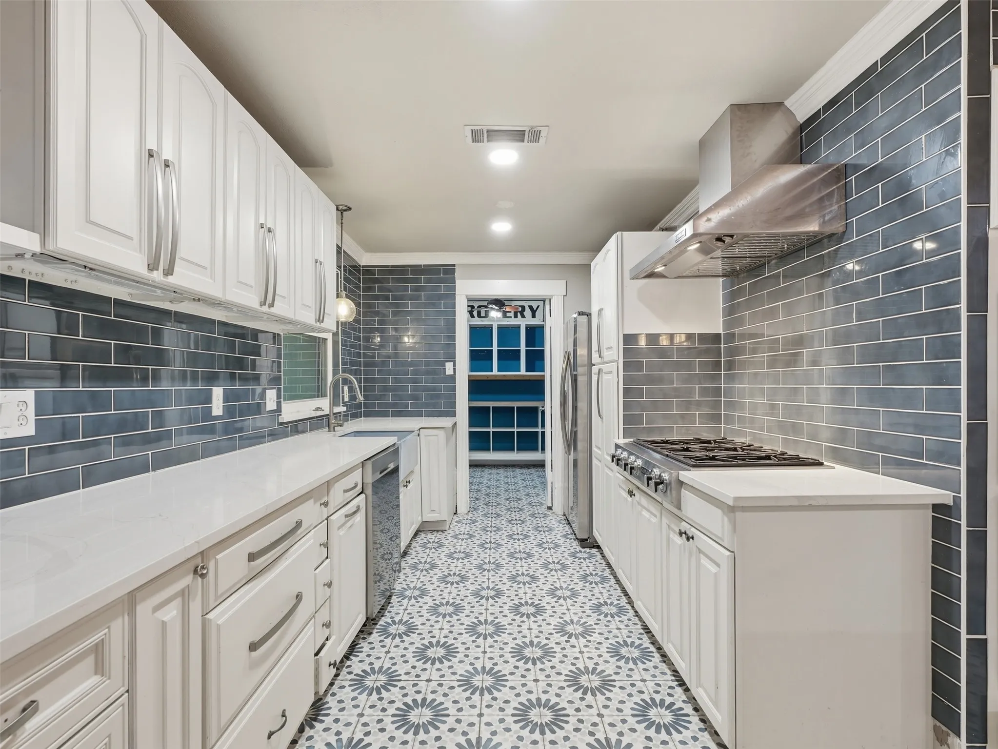 White cabinetry, light countertops, subway tile backsplash, patterned tile flooring, and stainless steel appliances