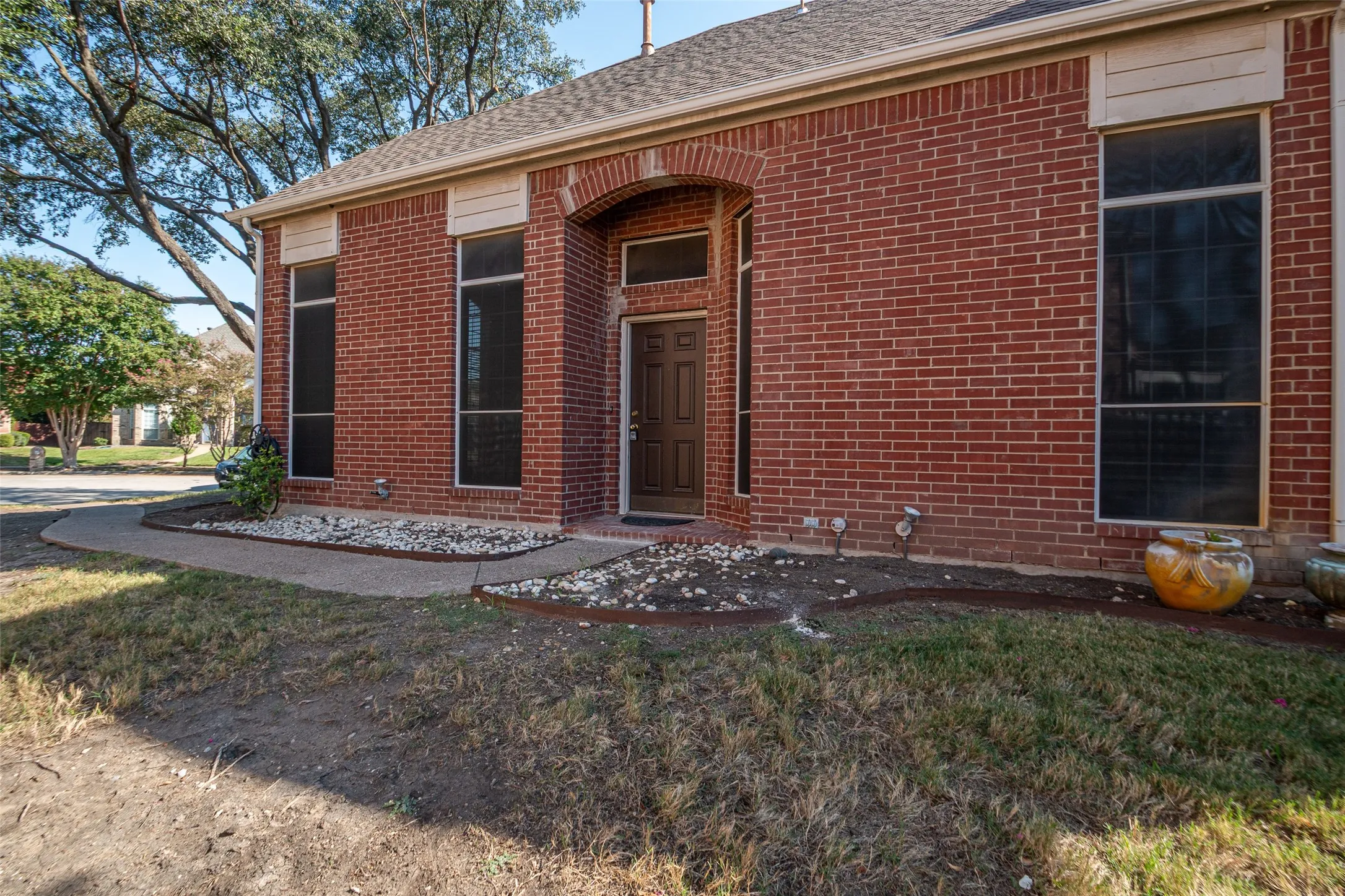 Red brick exterior with arched entryway, dark wood-paneled door, and vertical windows