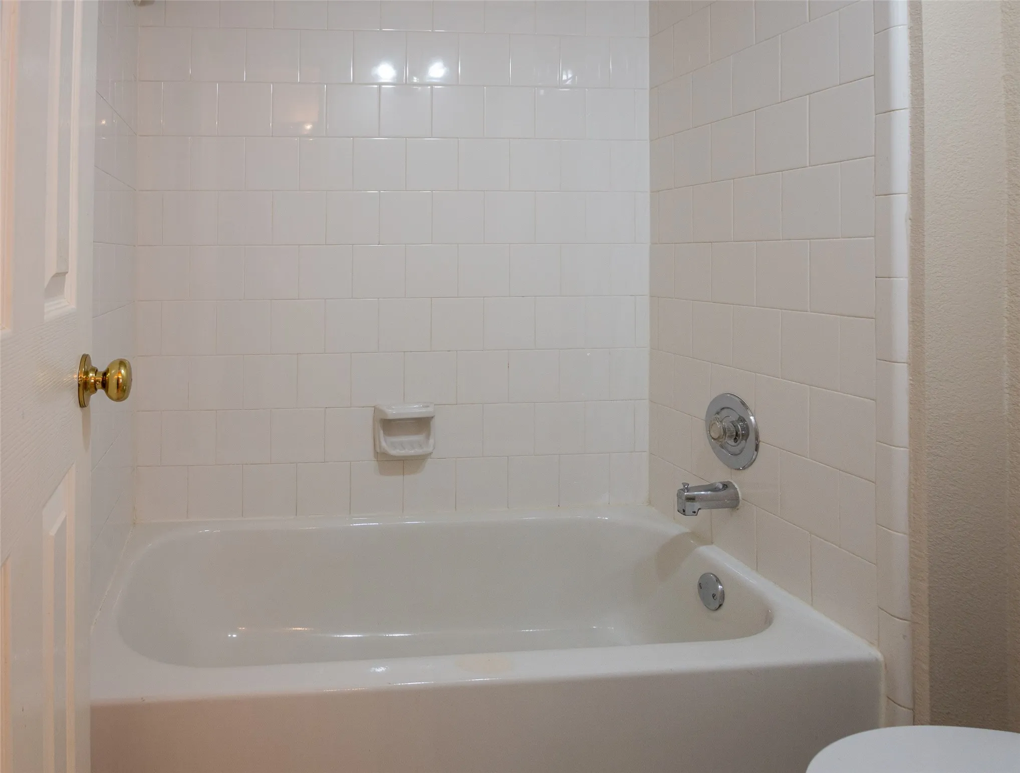 White subway tile surround, built-in bathtub, and chrome fixtures