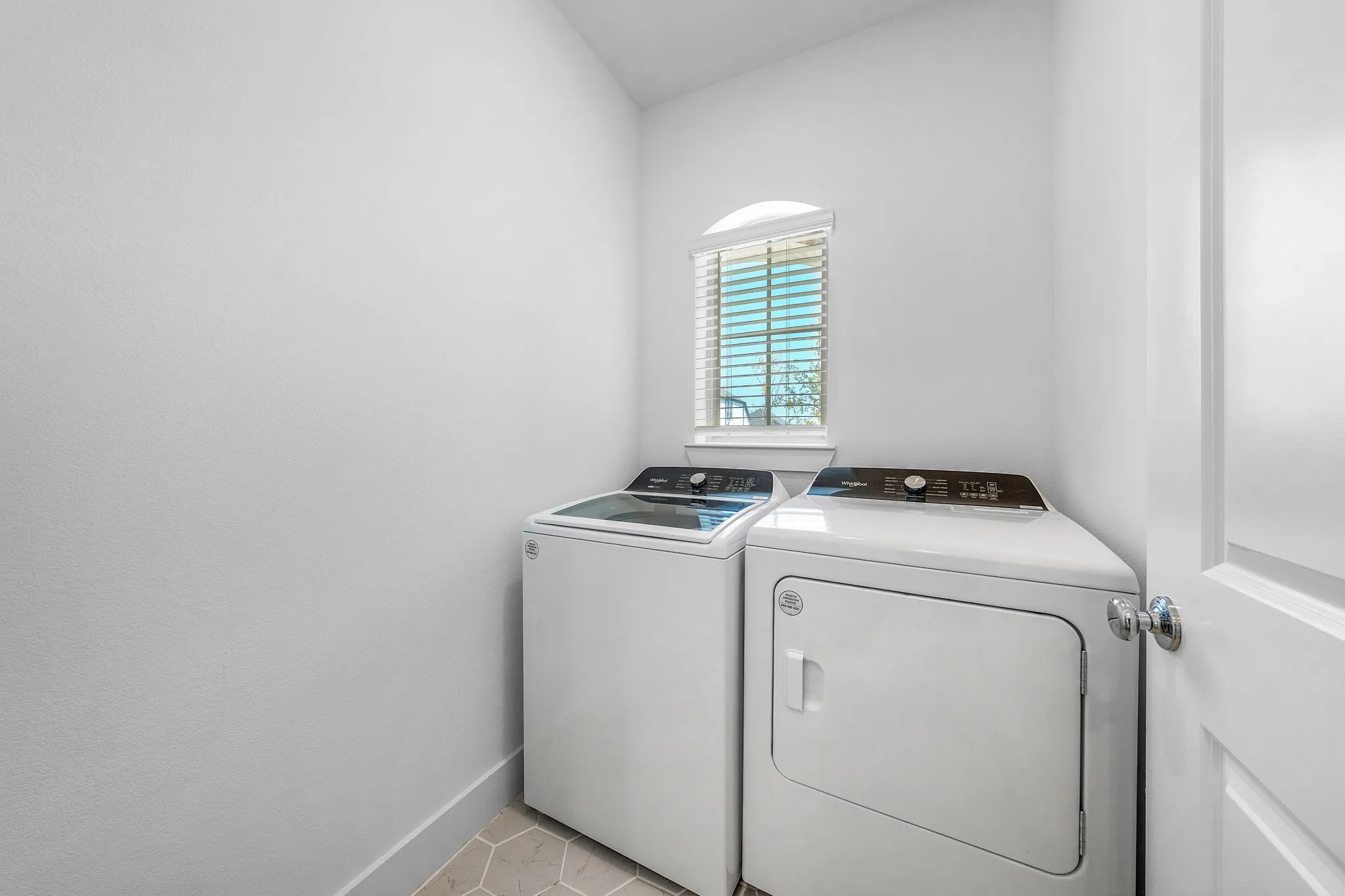 Laundry room featuring an arched window with blinds and hexagonal tile flooring
