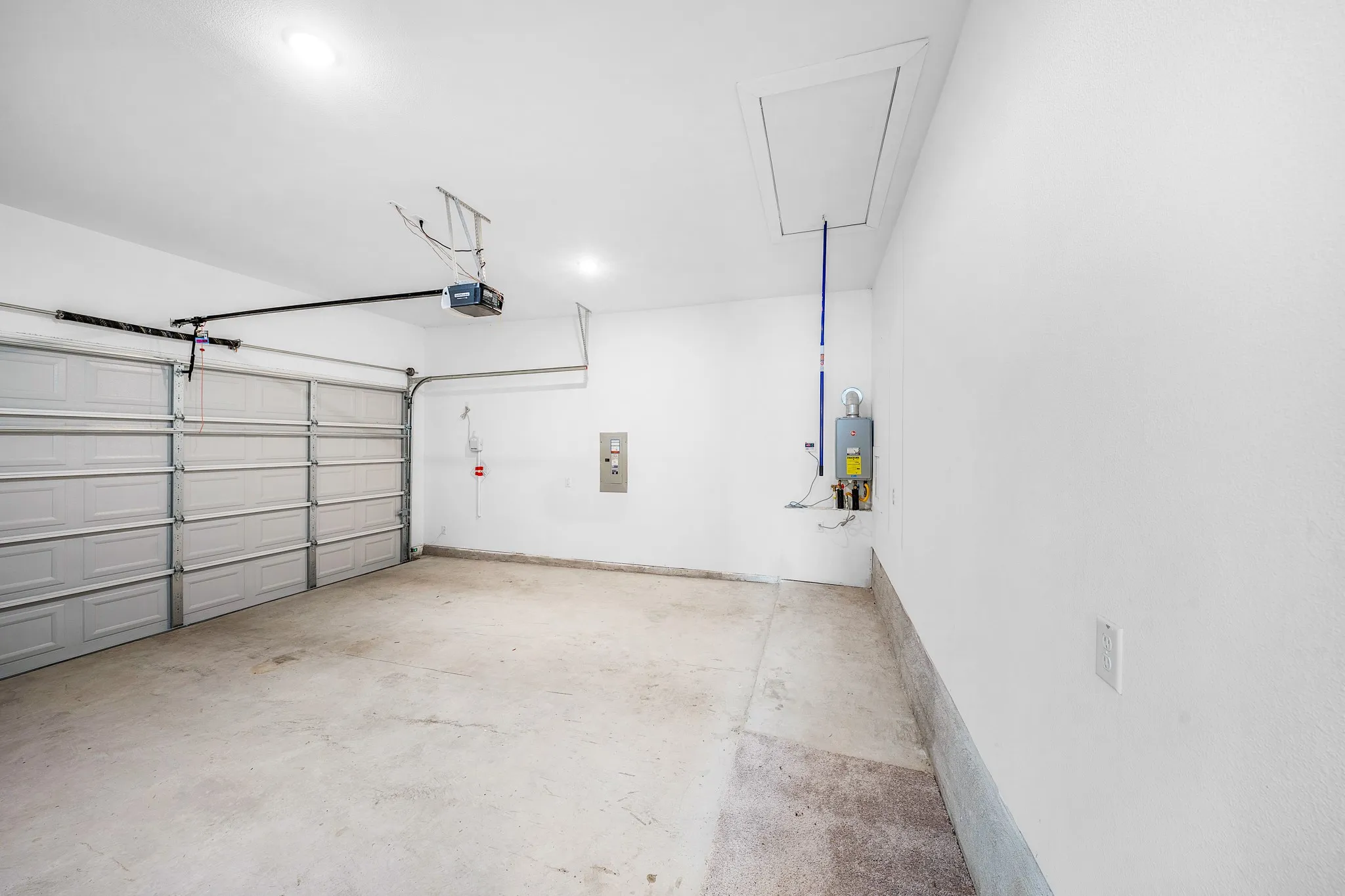 Attached garage with concrete flooring, two overhead doors, and an access panel
