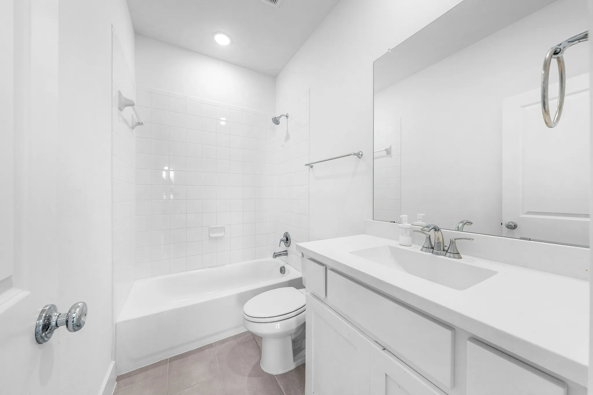 Full bathroom featuring a white tub, shower with subway tile surround, white vanity with integrated sink, and a large wall-mounted mirror