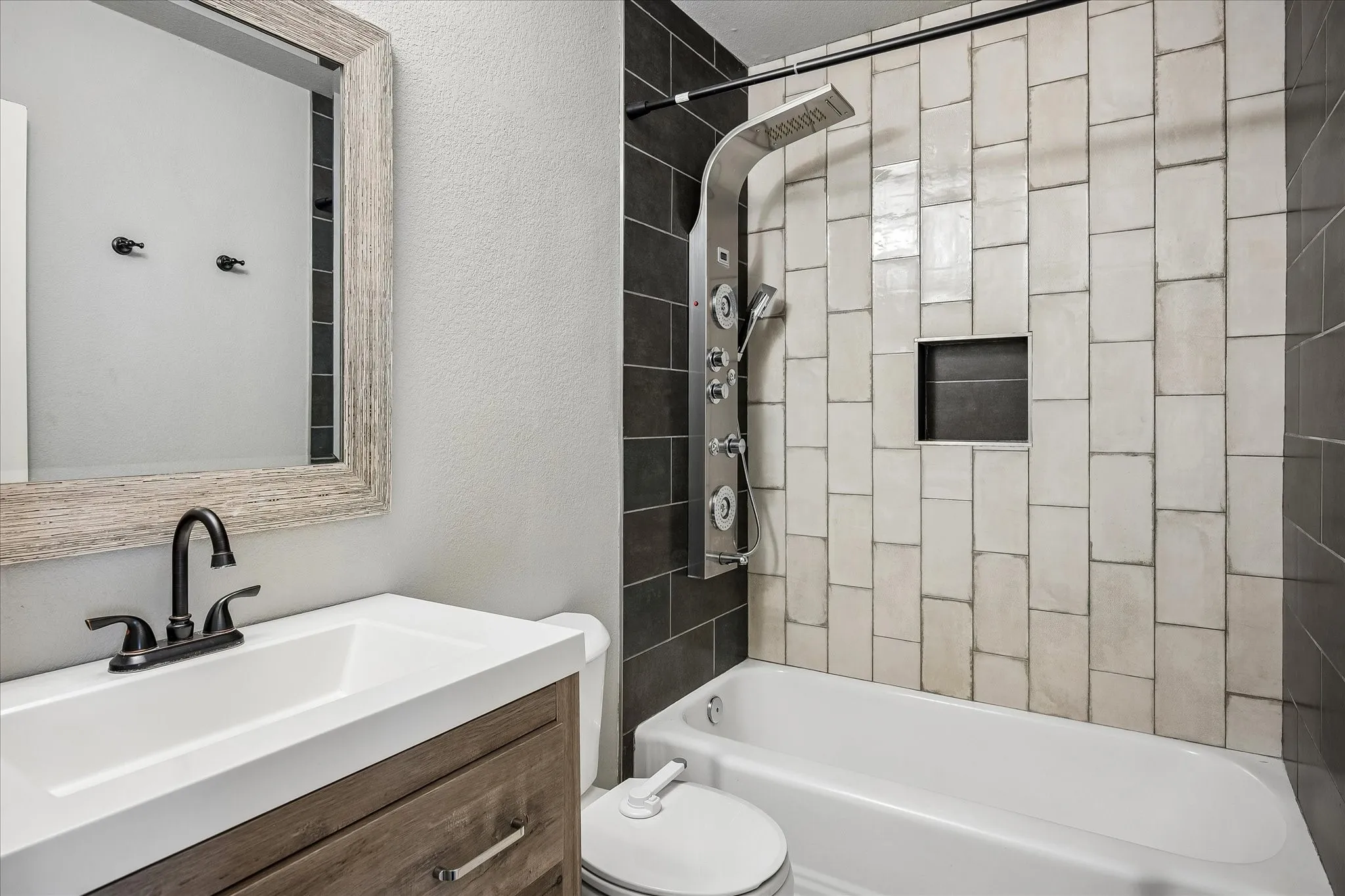 Bathroom featuring a wood-finish vanity, integrated sink, and dark bronze faucet