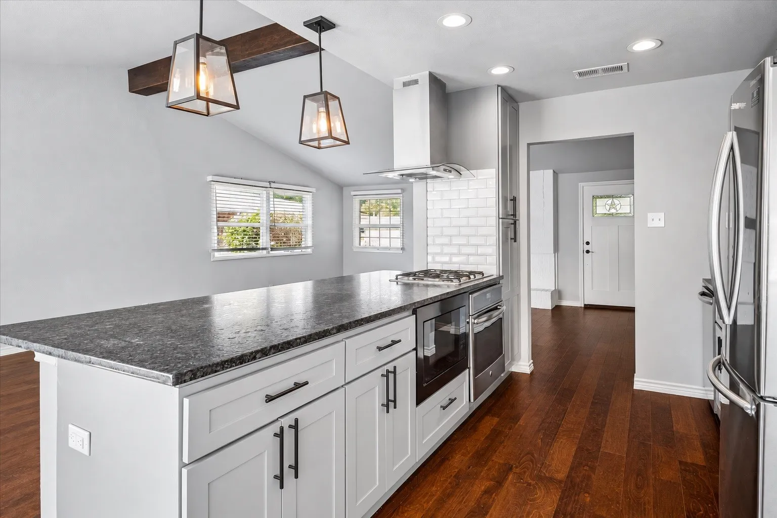 Kitchen featuring a large island with a stone countertop, built-in cooktop, and double ovens