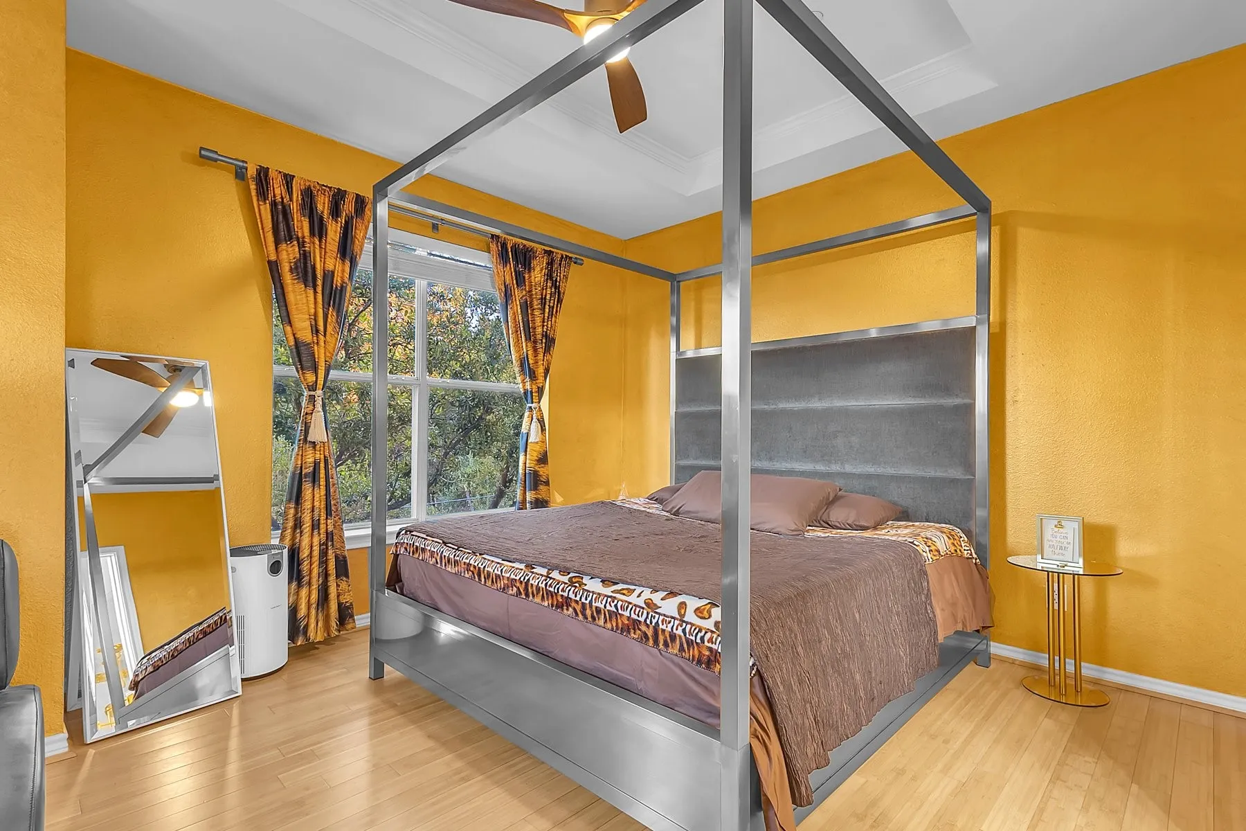 Primary bedroom with treetop views, engineered wood floors and a ceiling fan