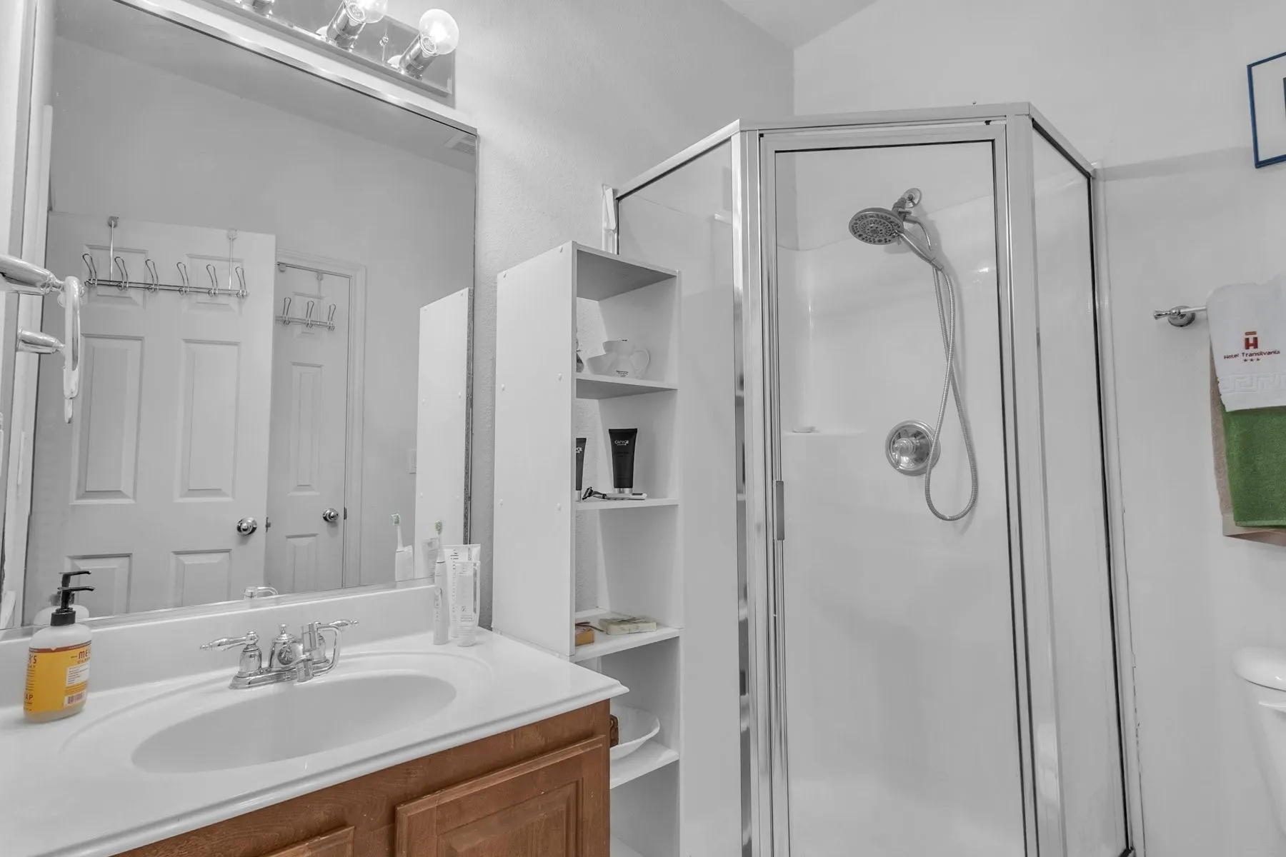 First-floor full bath with a walk-in shower, vanity and open shelving