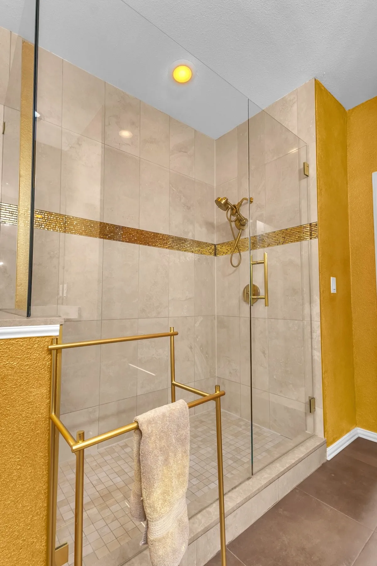 Oversized walk-in shower with frameless glass and decorative tile accents