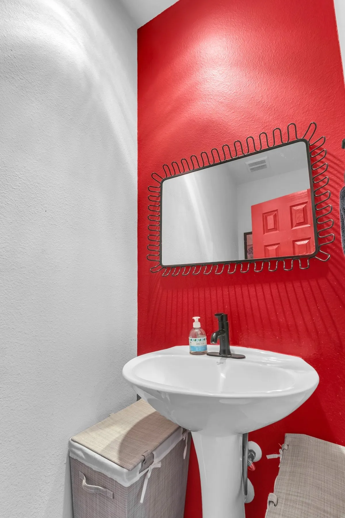 Second-floor half bath with a pedestal sink and a bold red accent wall