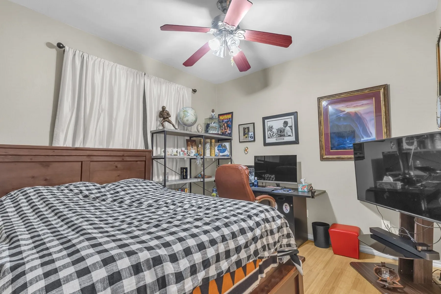 First-floor bedroom with a ceiling fan, engineered wood floors and a window