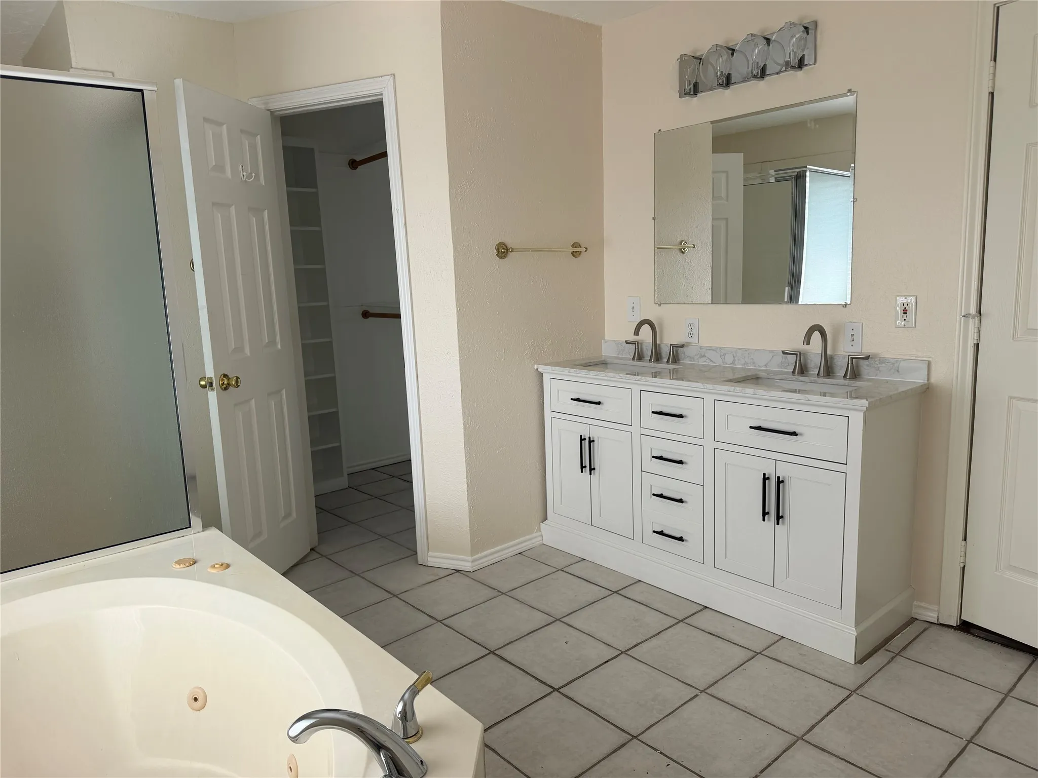 Dual vanity with undermount sinks, a large mirror, and overhead lighting