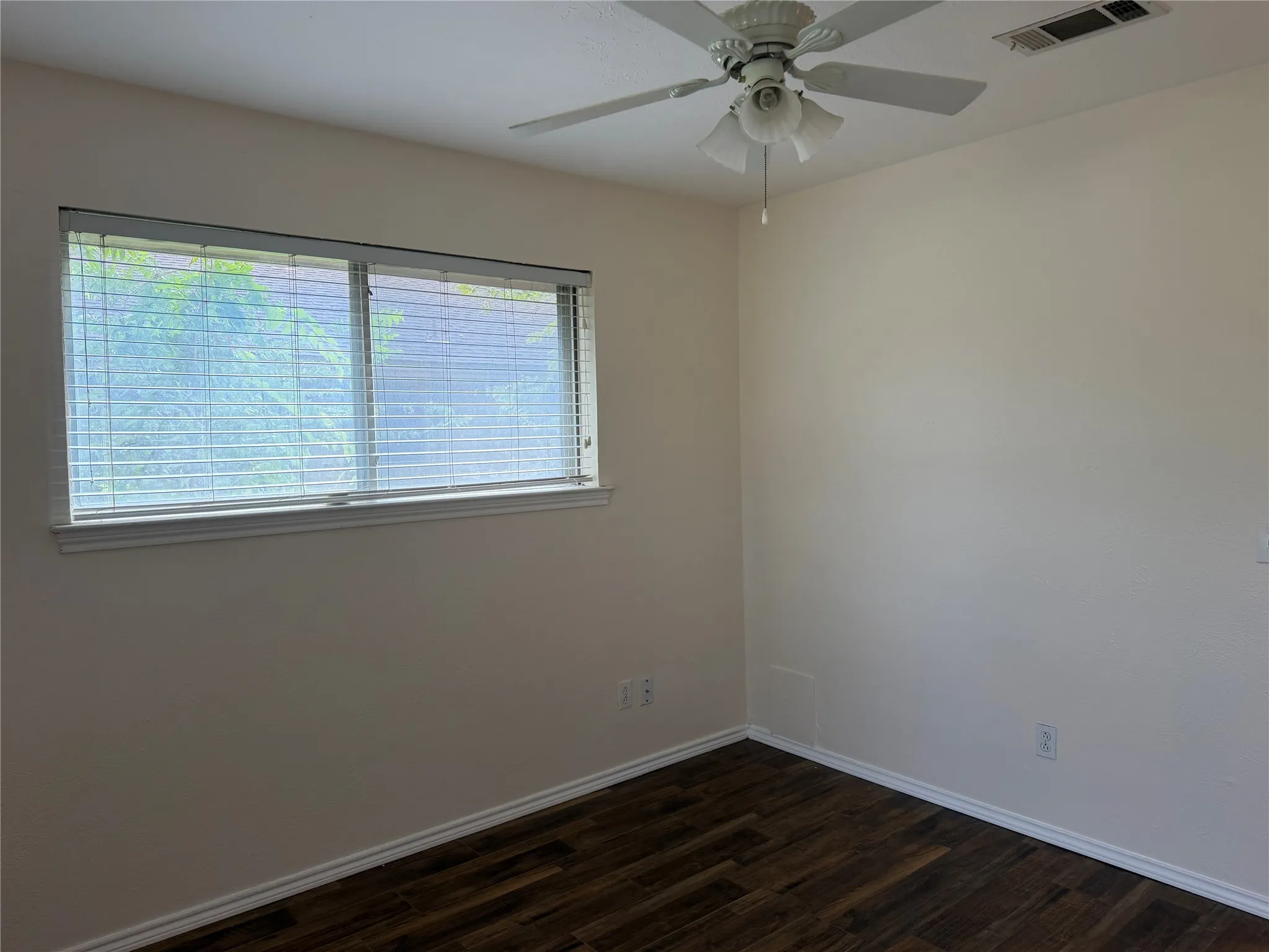 Warm neutral wall color, wood-finish flooring, white window trim, horizontal blinds, and a ceiling fan with integrated lighting