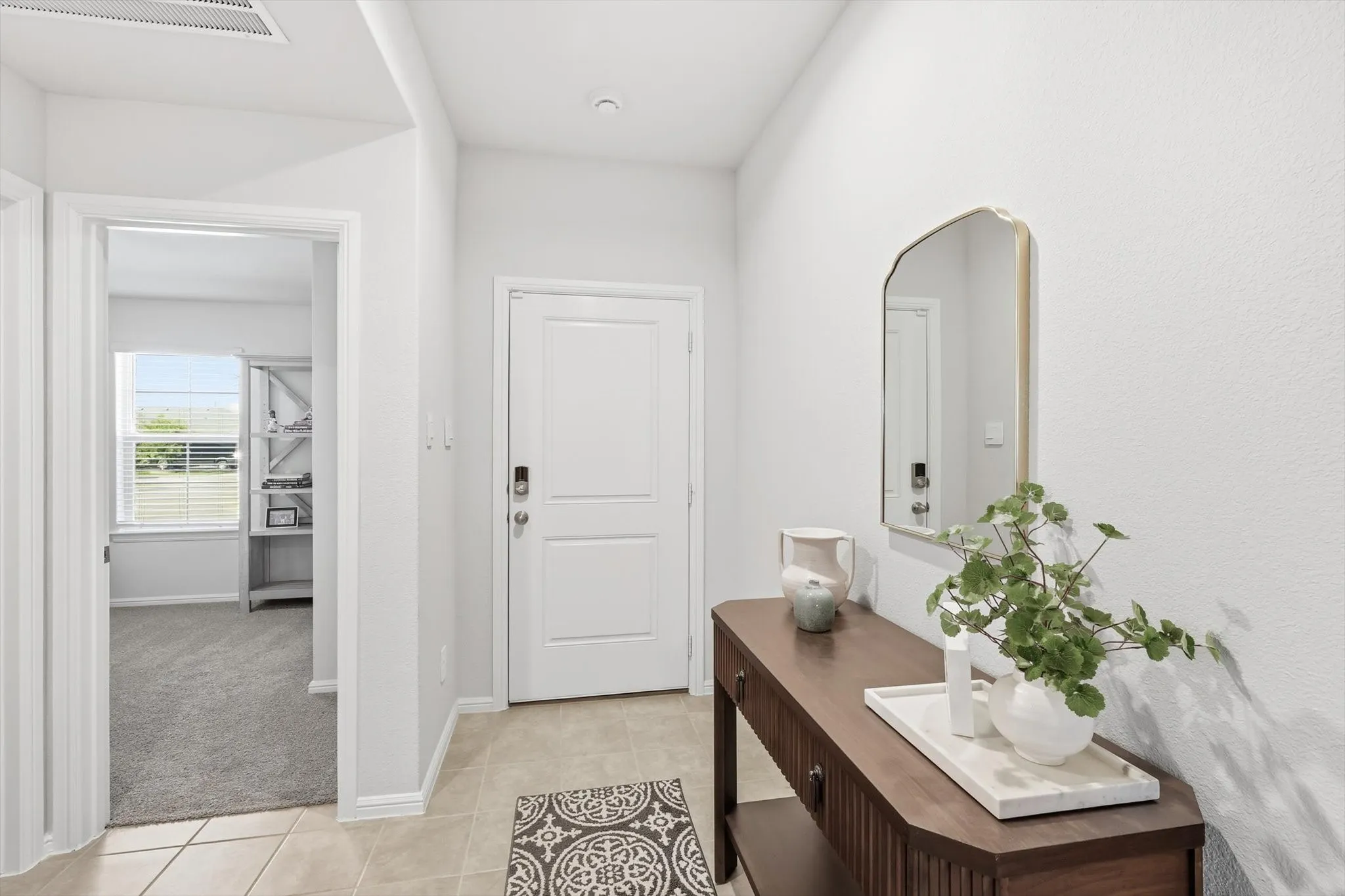 Light neutral wall tones throughout, featuring a solid white panel door with smart lock hardware, and square tile flooring in the entry