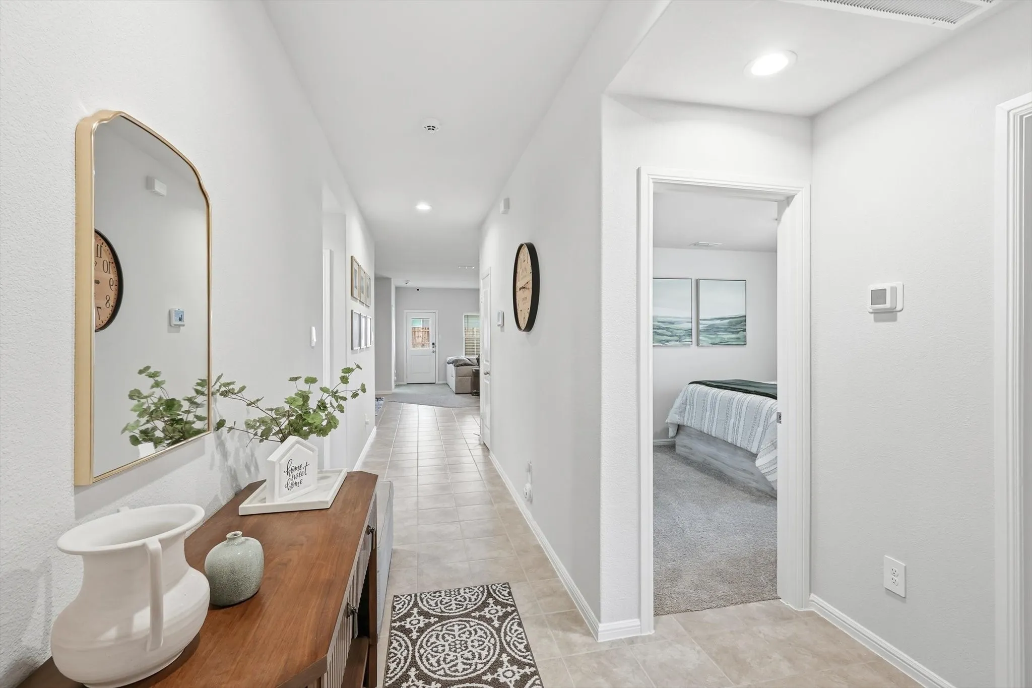 Recessed lighting illuminates the hallway, featuring tile flooring and light-toned walls