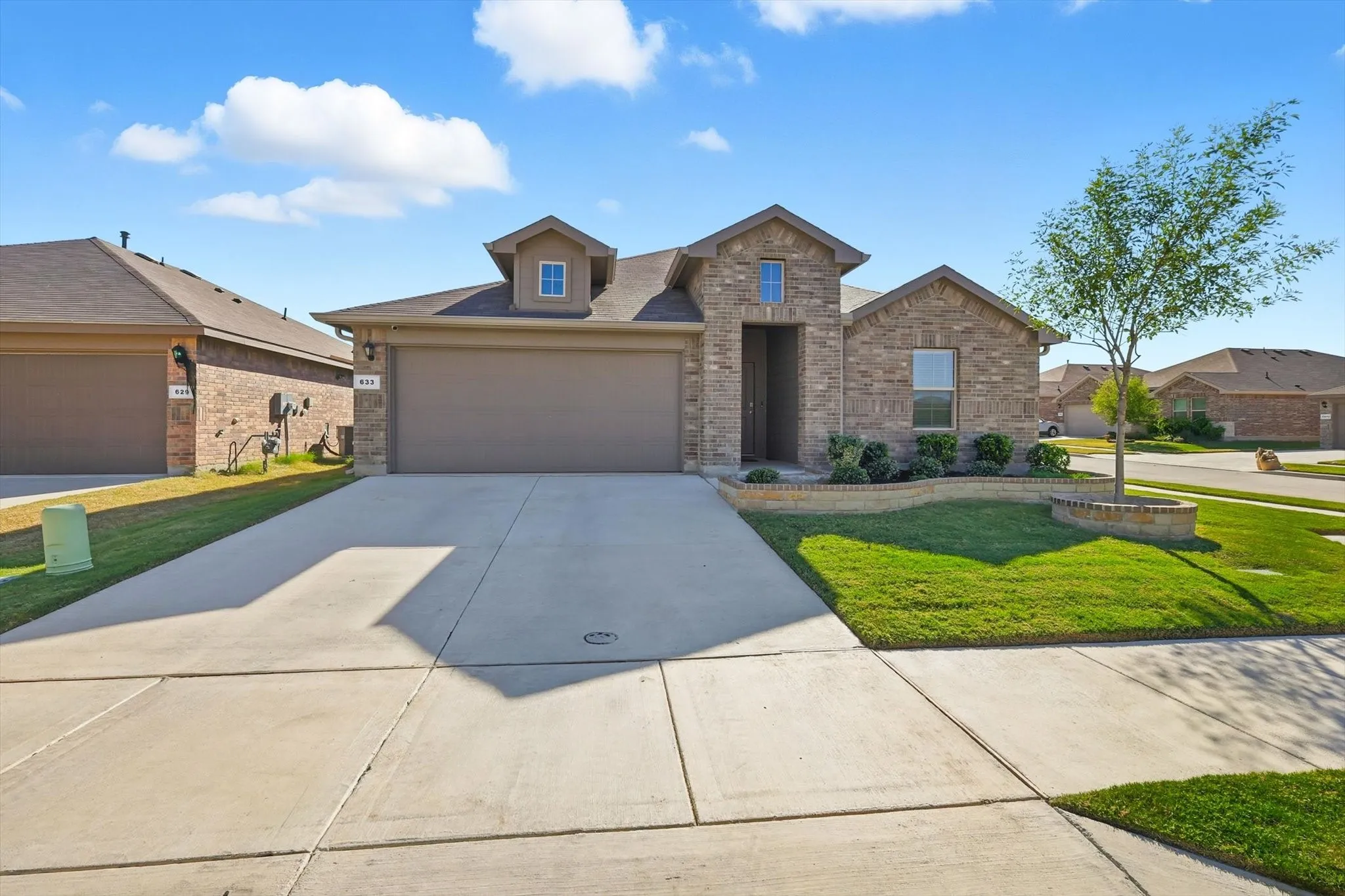 Brick exterior, attached garage, concrete driveway, landscaped front yard, raised planter beds