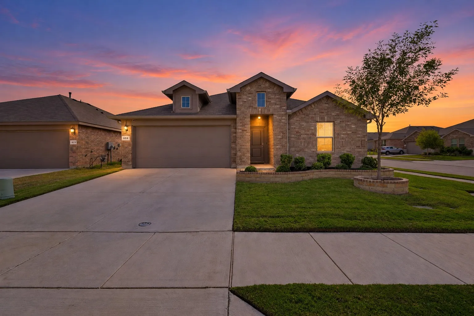 Brick exterior with a stone accent entry, two-car garage, concrete driveway, and front lawn landscaping