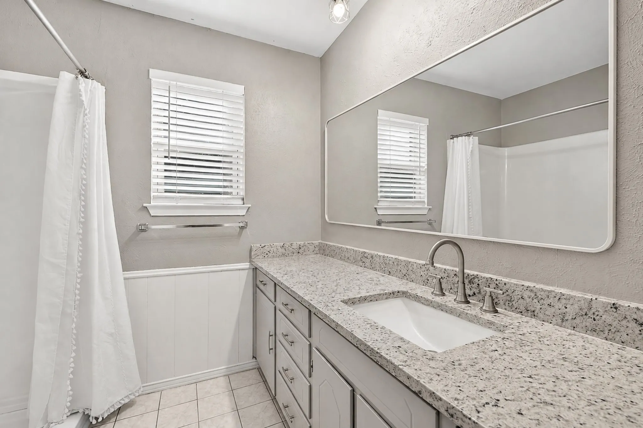 Double vanity with a rectangular undermount sink, speckled countertop, and brushed nickel faucet